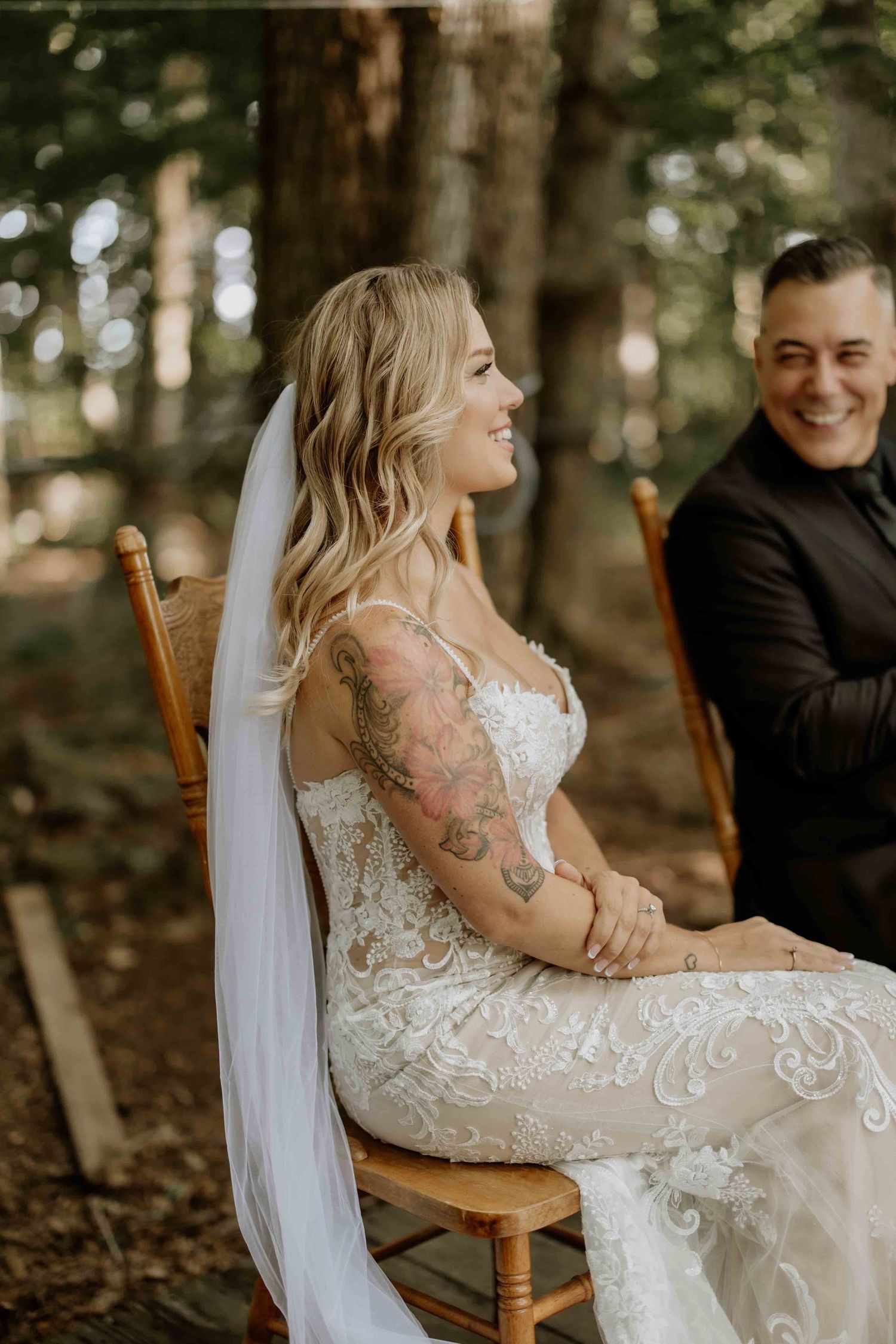 Couple shares intimate moment in wooden chair during forest photoshoot.