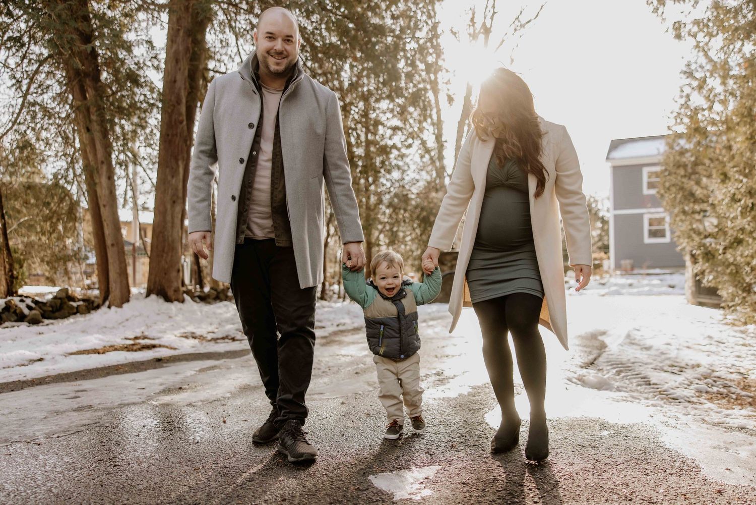 Family walking together on snowy path during winter day.