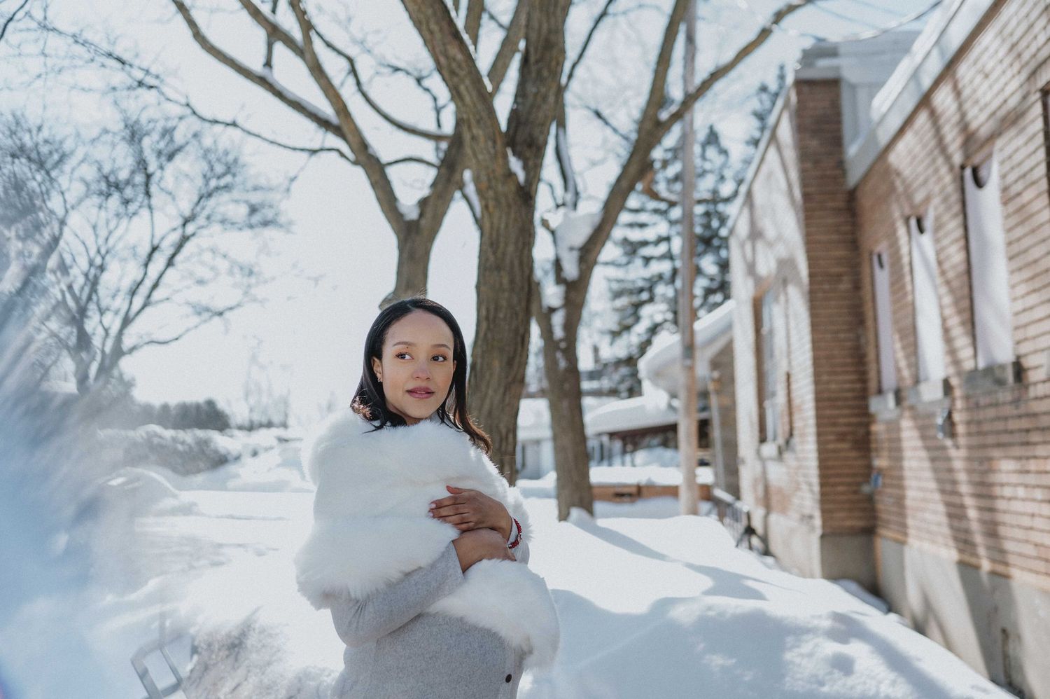 Winter family photoshoot with snow-covered trees and houses in the background.