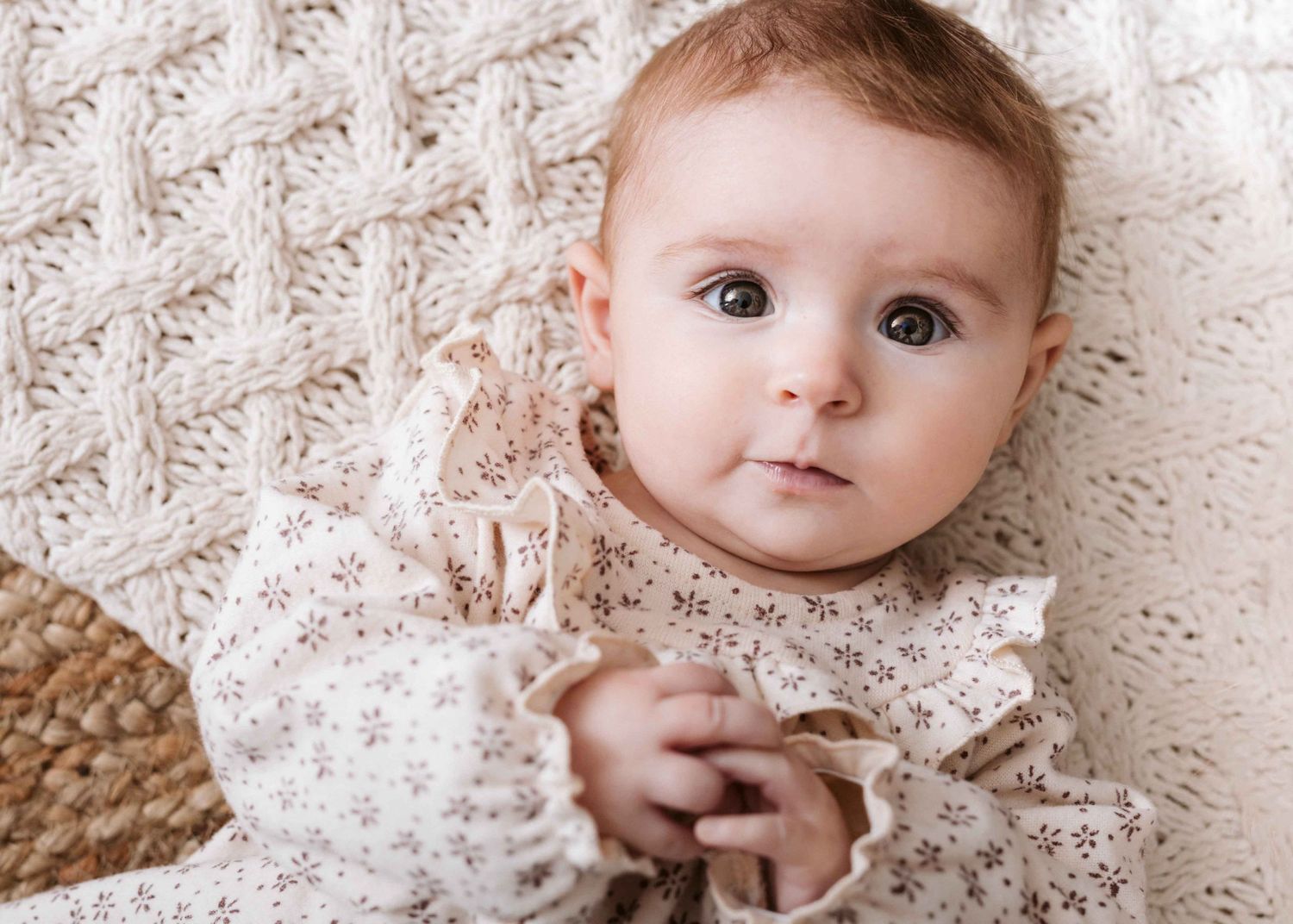 Baby lying on white lace blanket in close-up portrait series.
