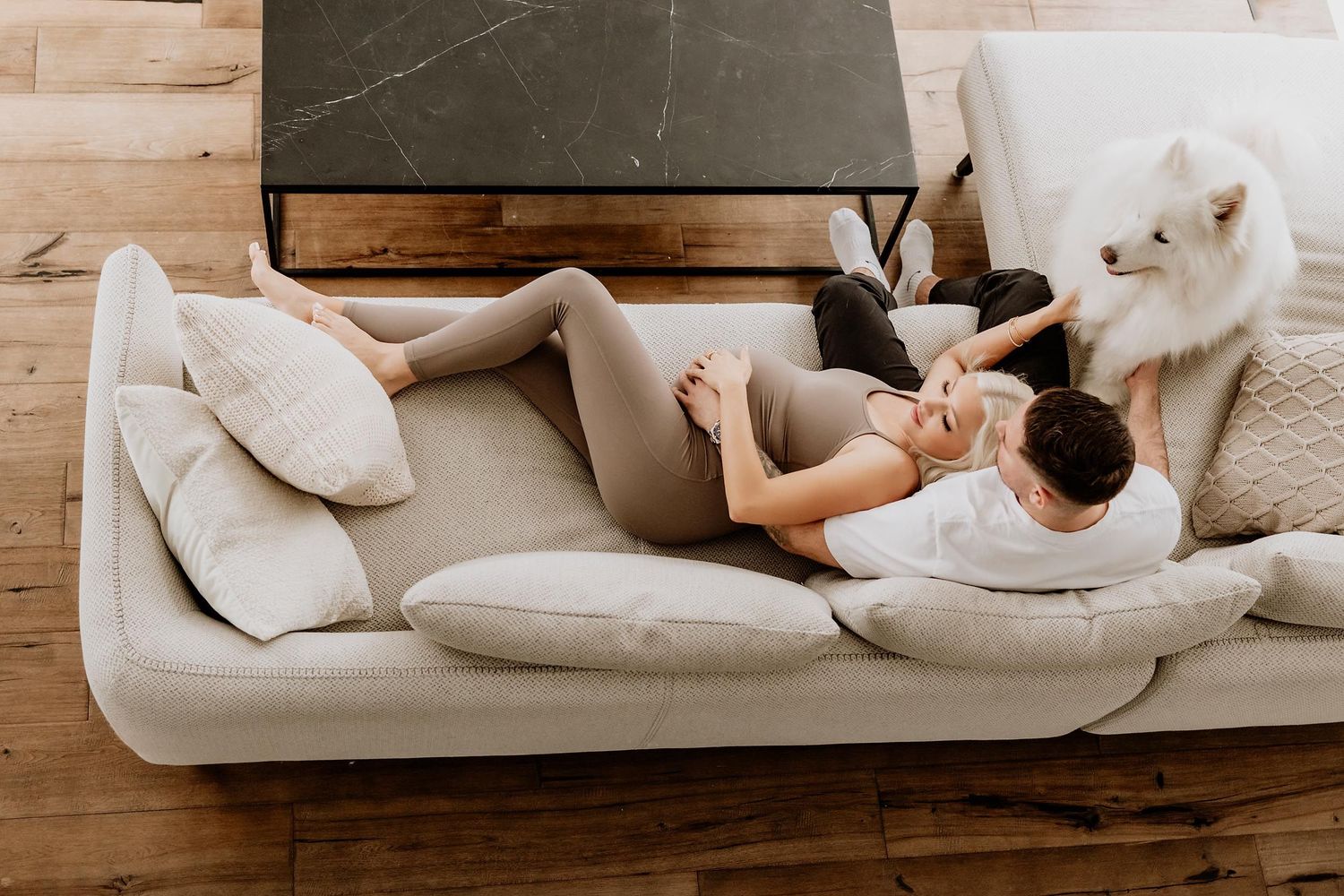 Cozy indoor scene with people relaxing on a white sectional sofa.