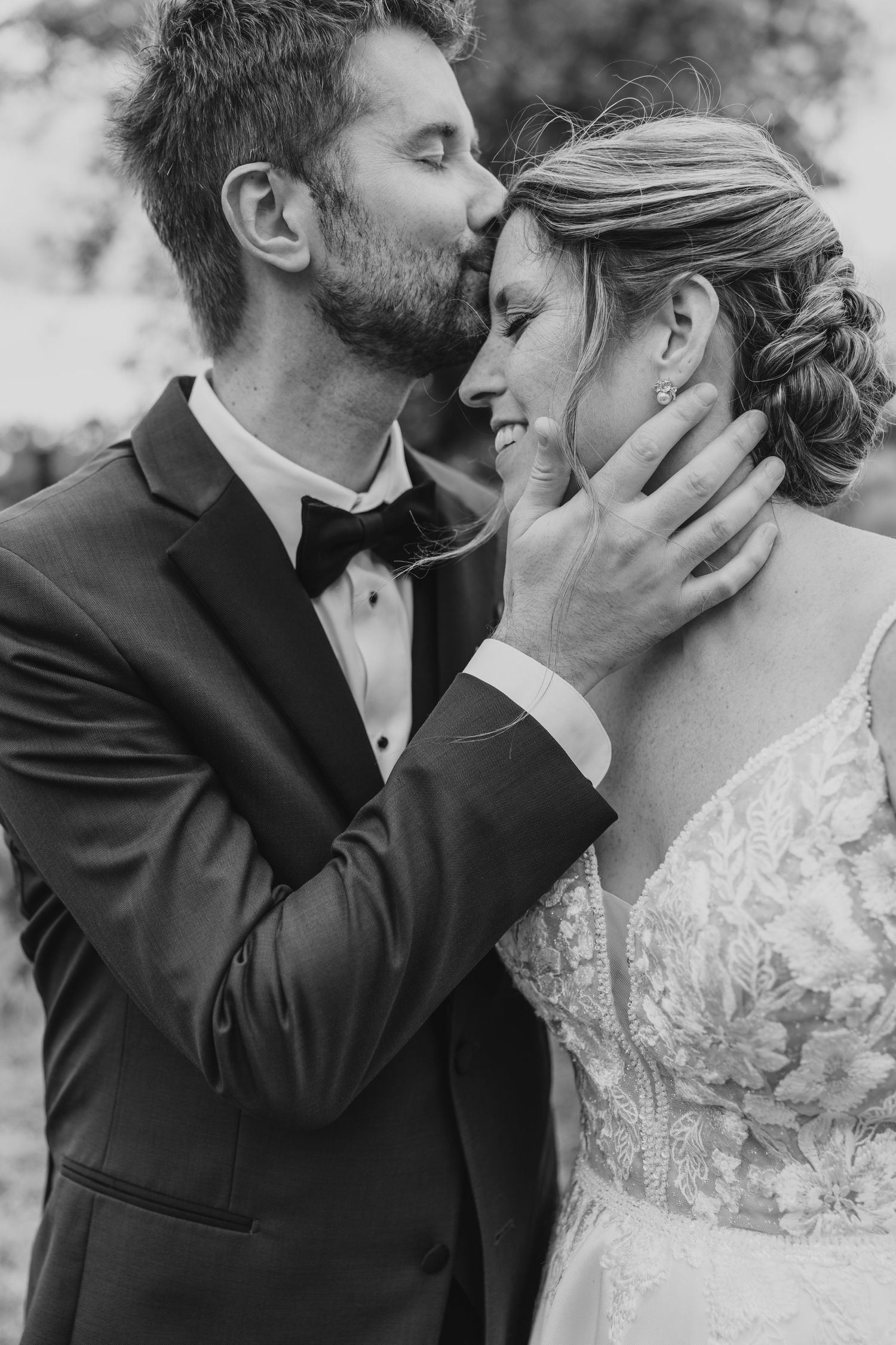 A tender black and white wedding moment captured as a couple shares an intimate embrace outdoors.