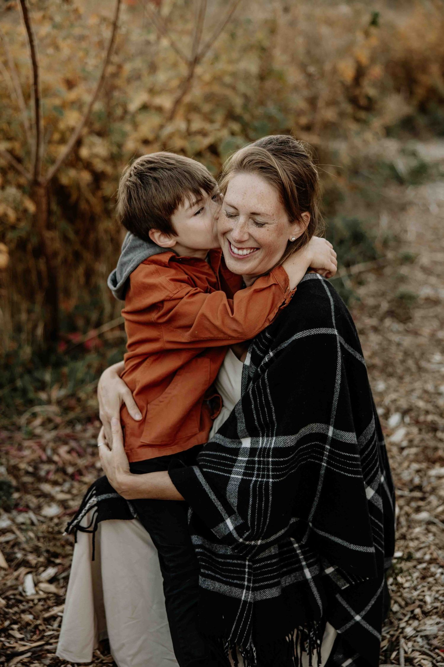 Tender moment between parent and child embracing outdoors in fall setting.