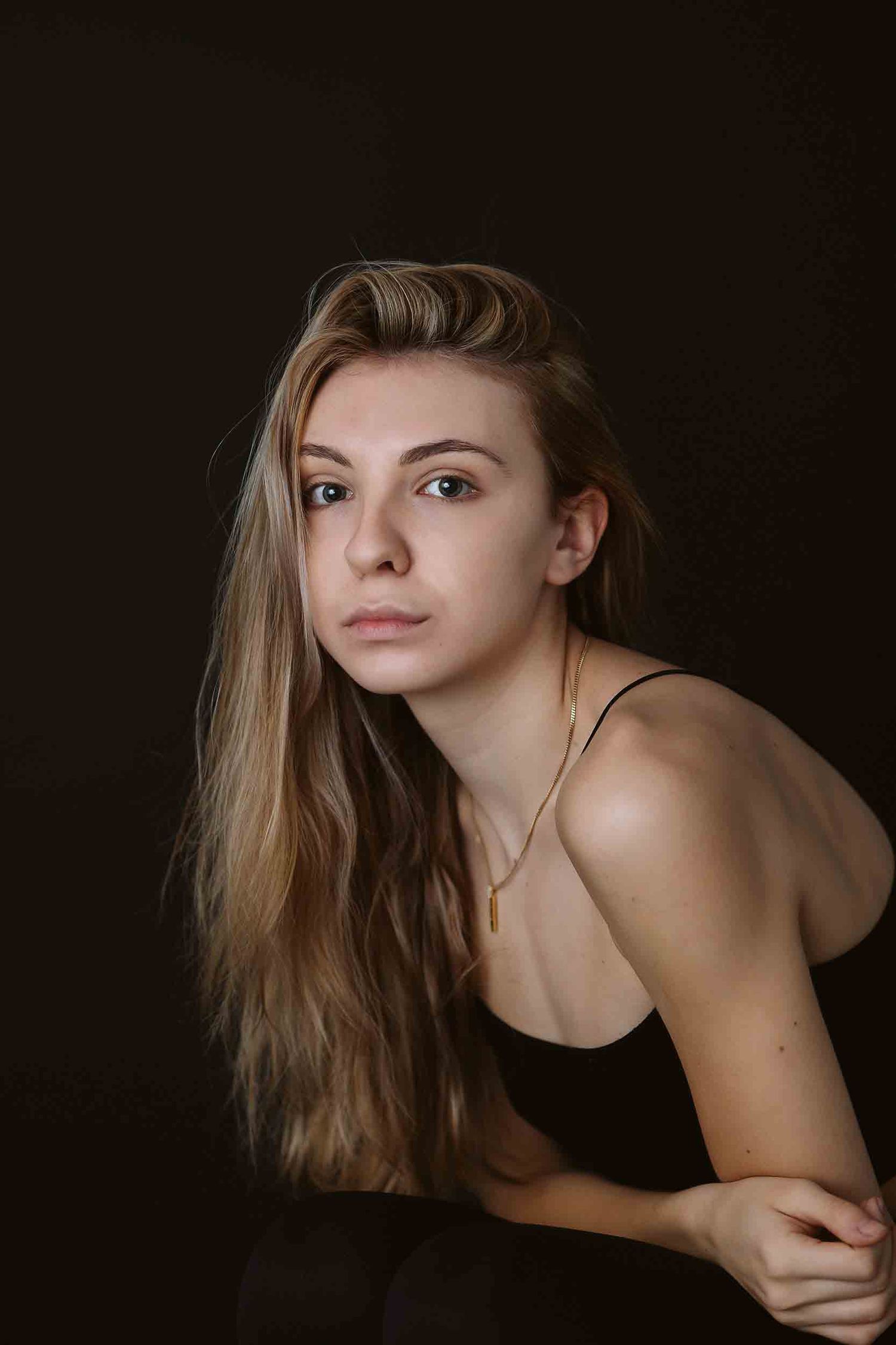 Dramatic studio portrait with natural lighting and minimalist styling.