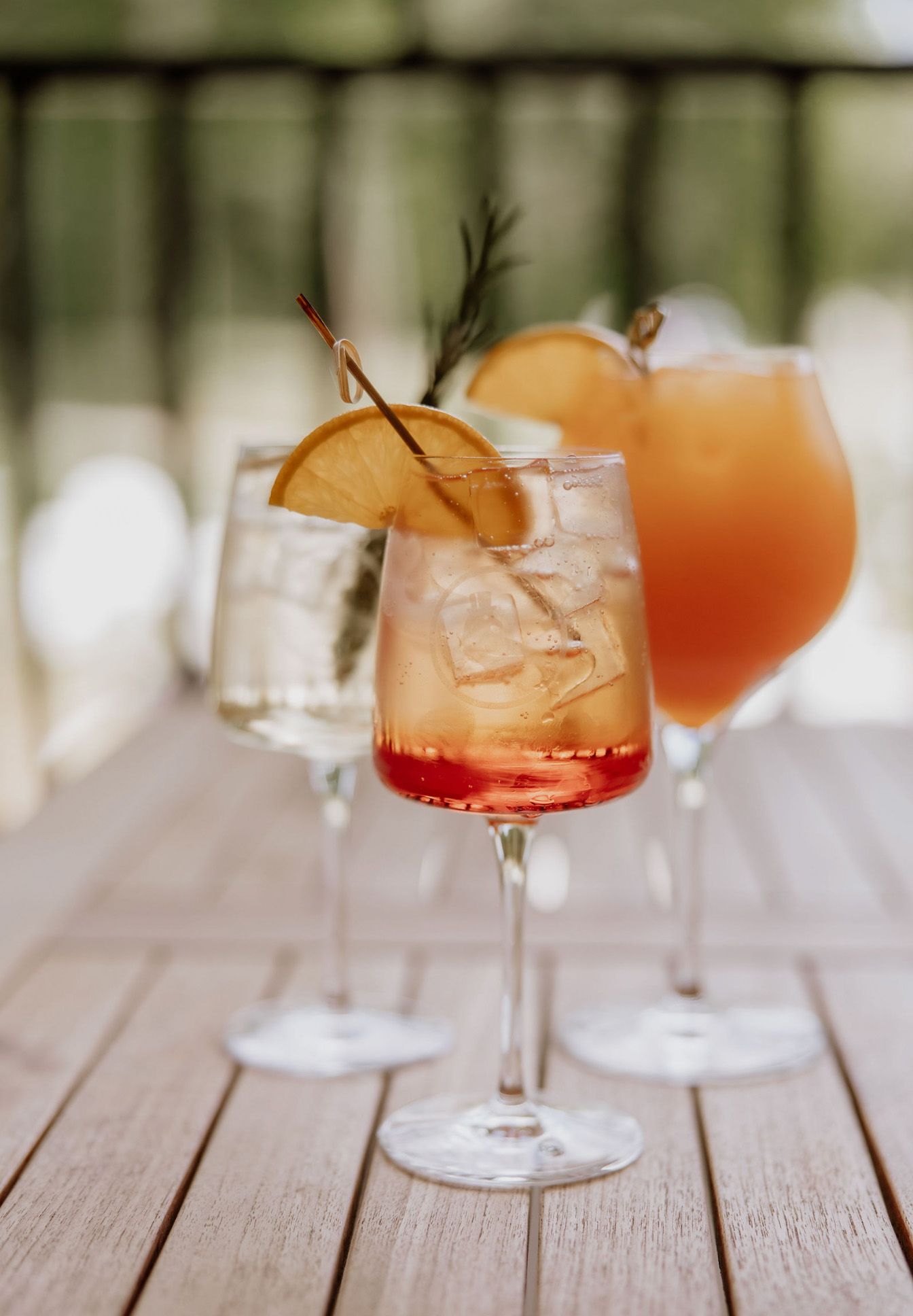 Orange cocktails with ice garnished with citrus on a wooden table in soft natural lighting.