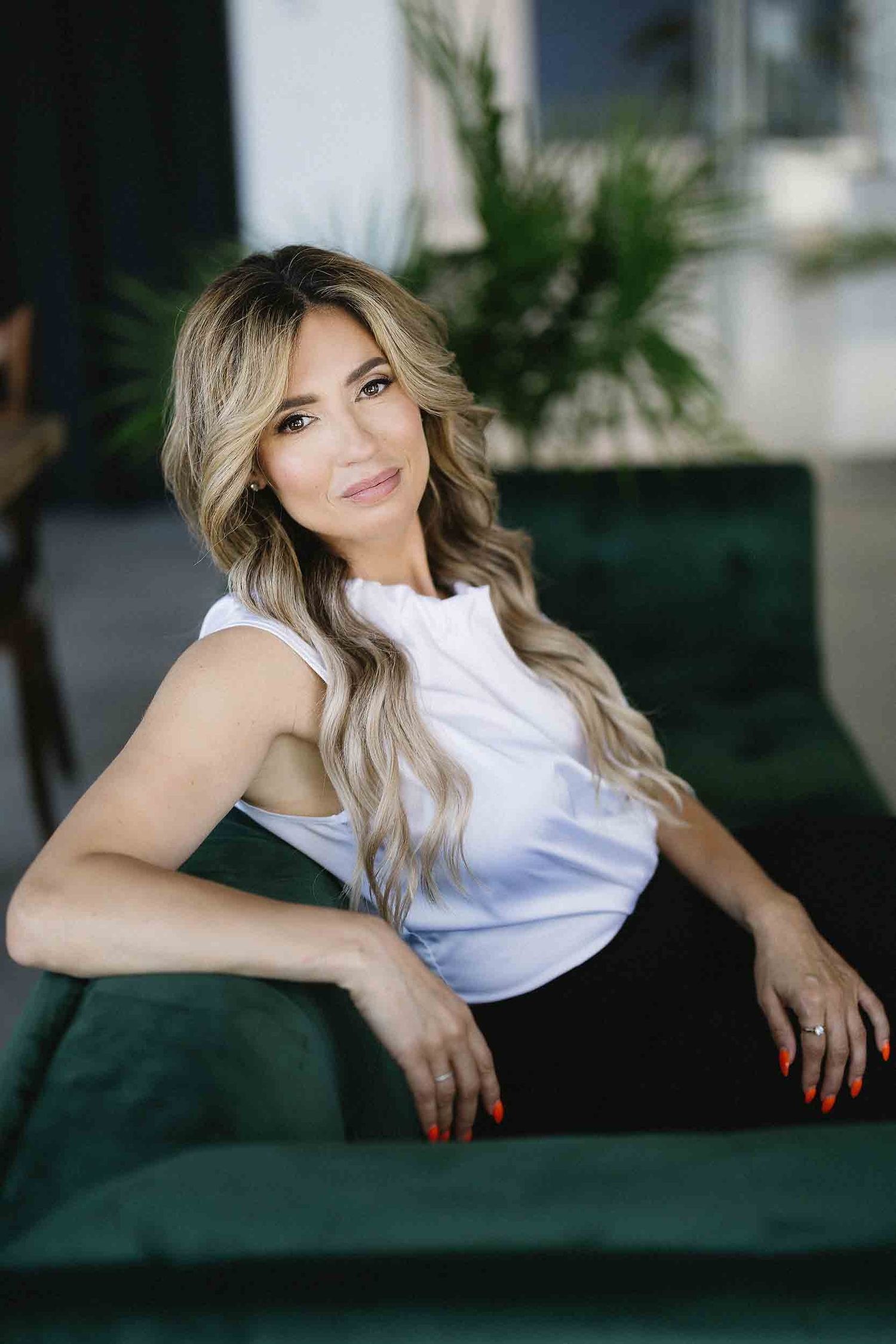 Casual portrait series on green velvet couch wearing white top with natural lighting.