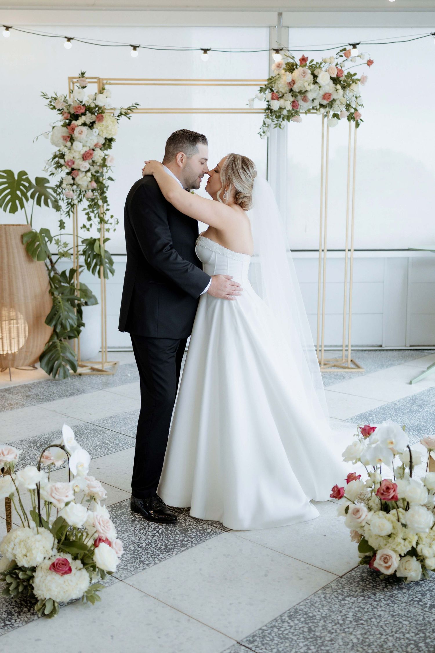 Modern wedding venue decorated with floral arrangements and string lights for reception.