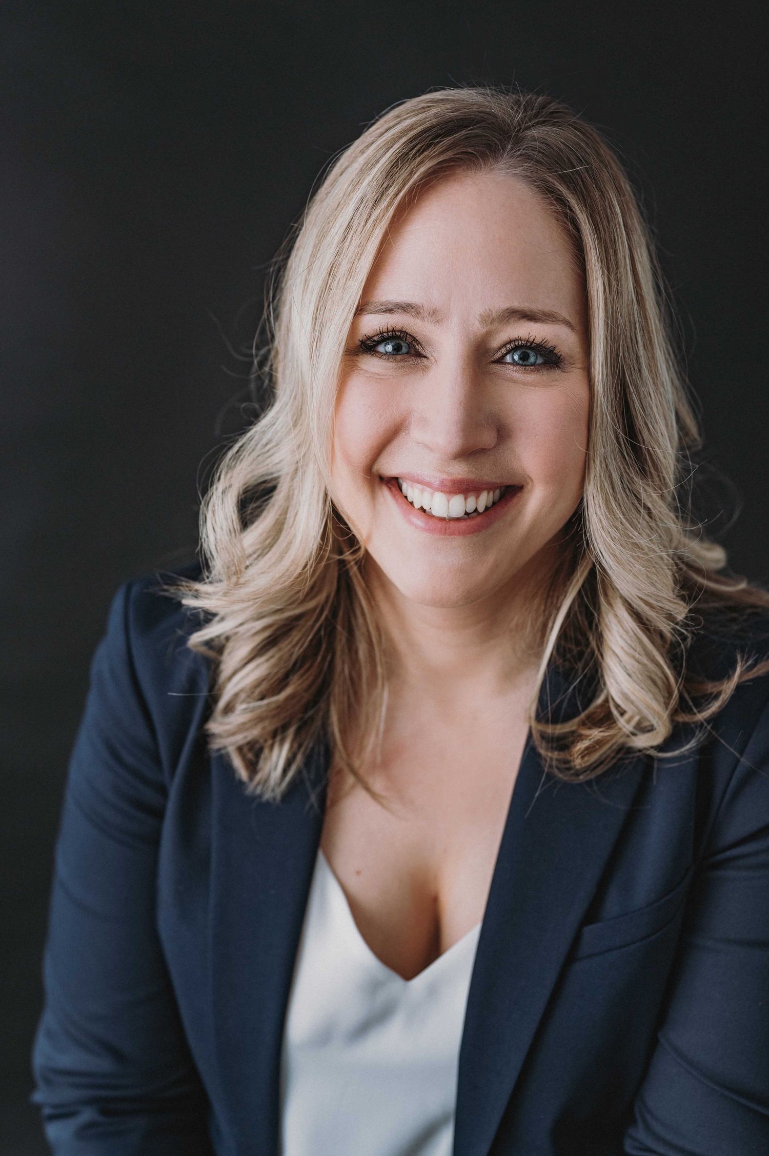 Professional headshots of woman in navy blazer against dark background.
