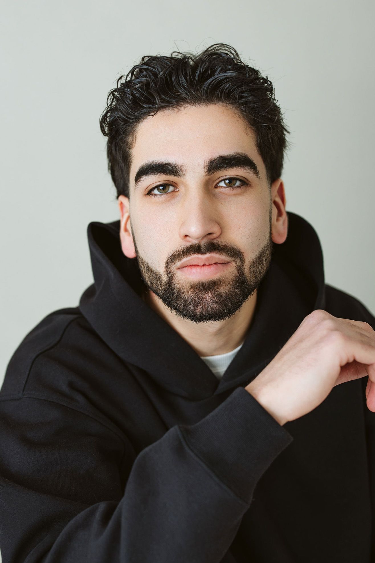Person in black hoodie posing against light background showing different angles.