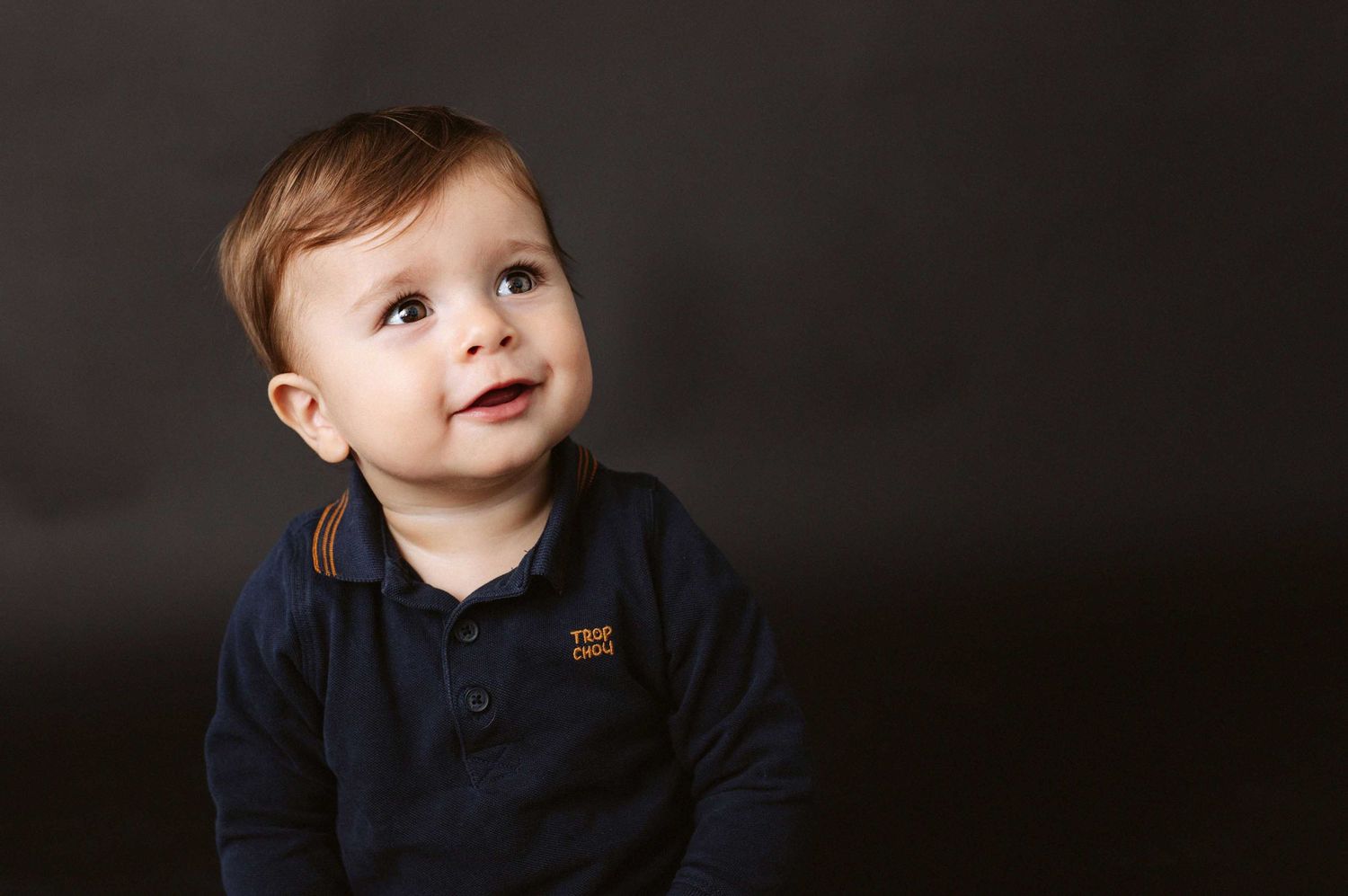 Series of baby portraits against a dark background showing joyful expressions.