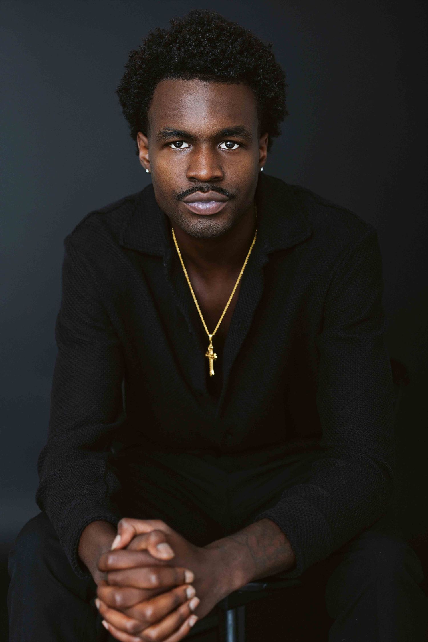 Professional studio portrait series showing dramatic lighting and black clothing against dark background.