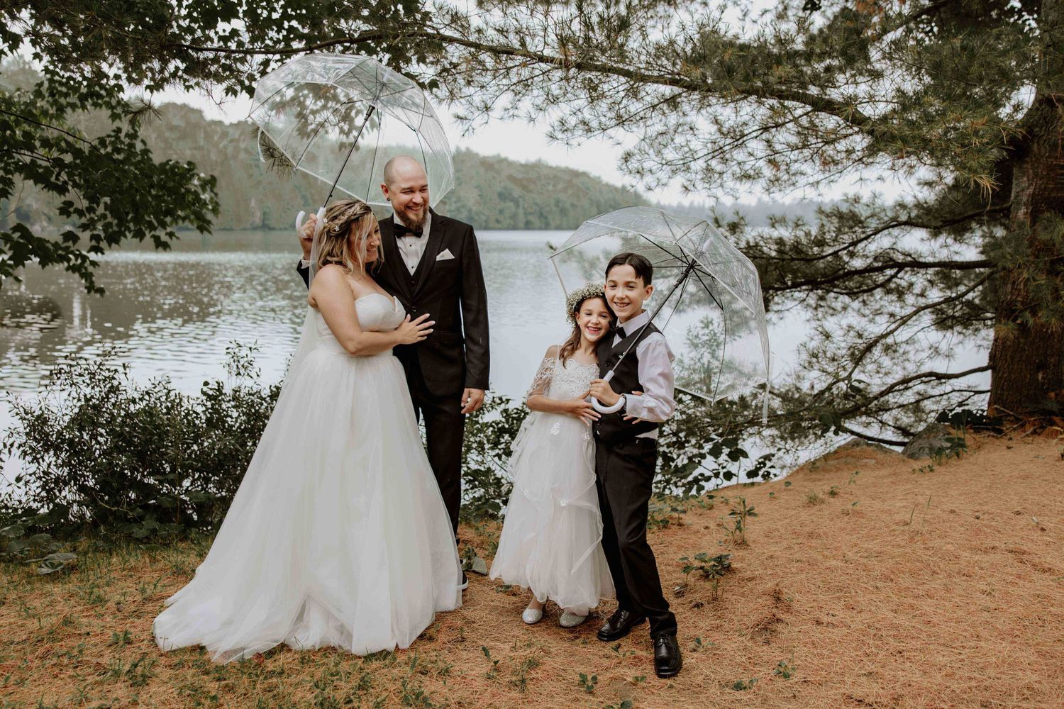 Wedding portrait of couples posing by a lake with mountains in the background.