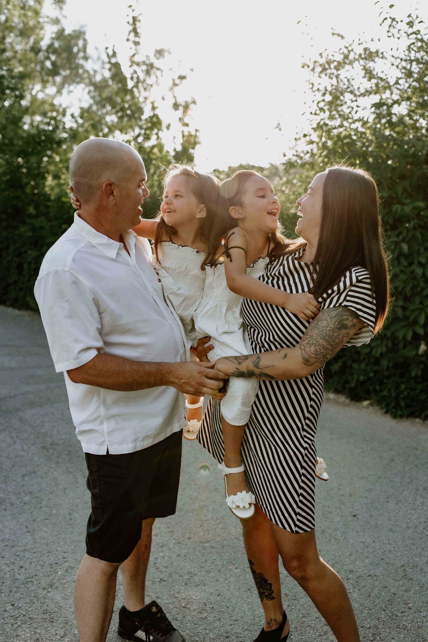 Family of four sharing joyful moment together during sunset photoshoot.