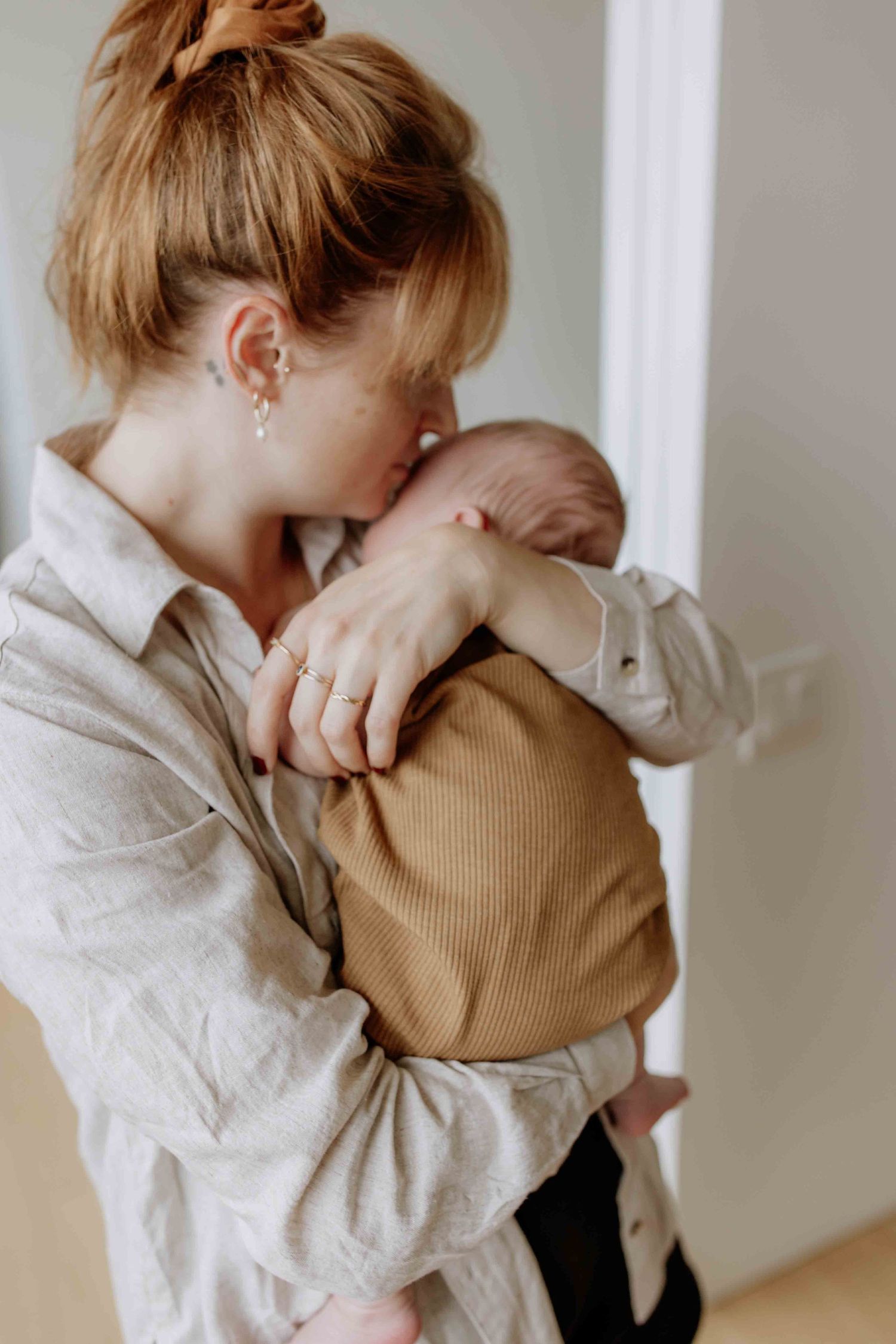 Tender moment between parent and newborn in soft, natural indoor lighting.