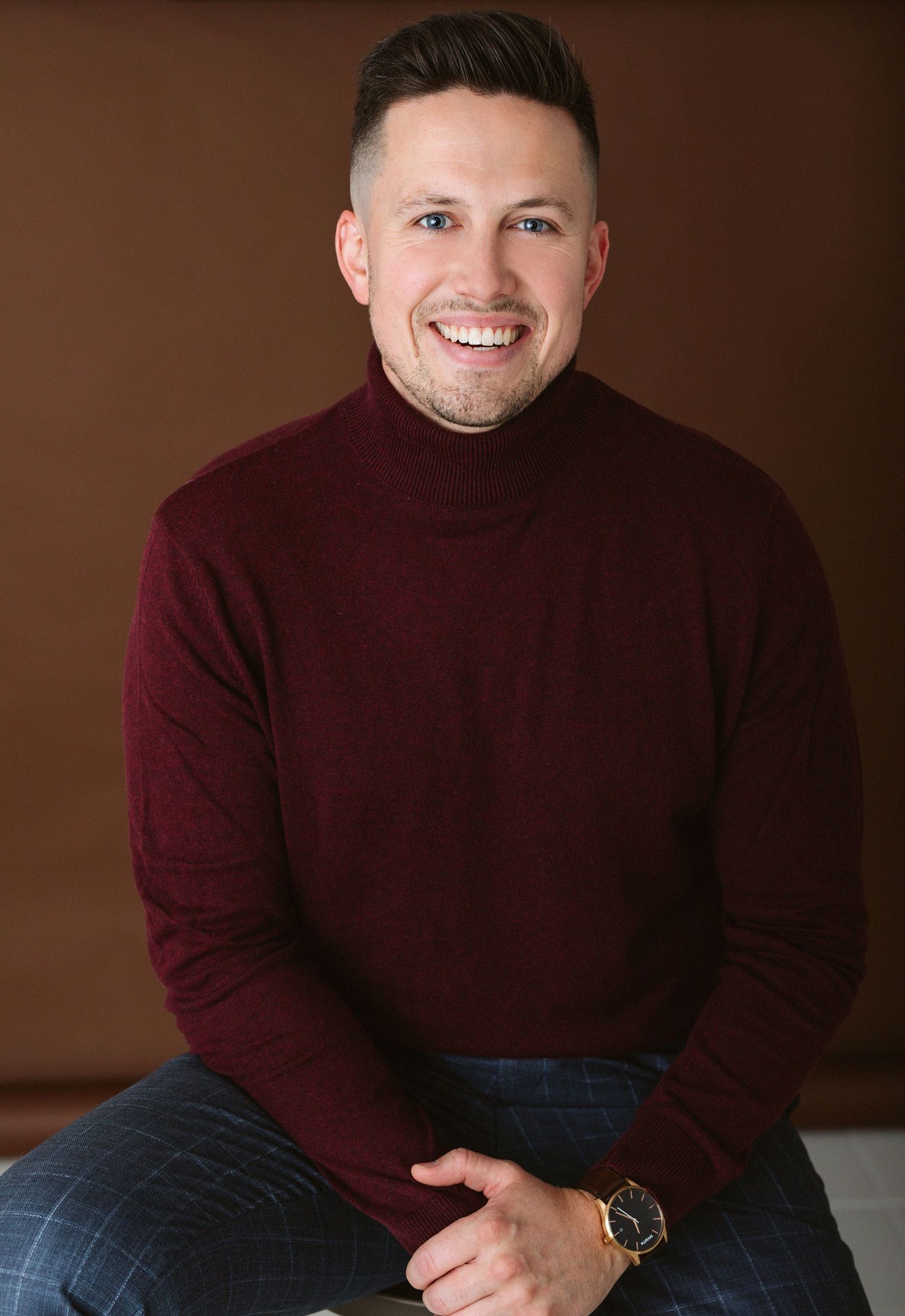 Person wearing burgundy turtleneck sweater sitting casually during portrait session.