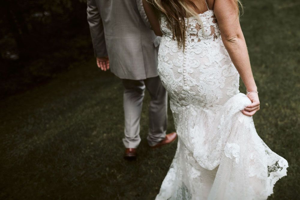 Close-up details of lace wedding dress with intricate beading against dark background.