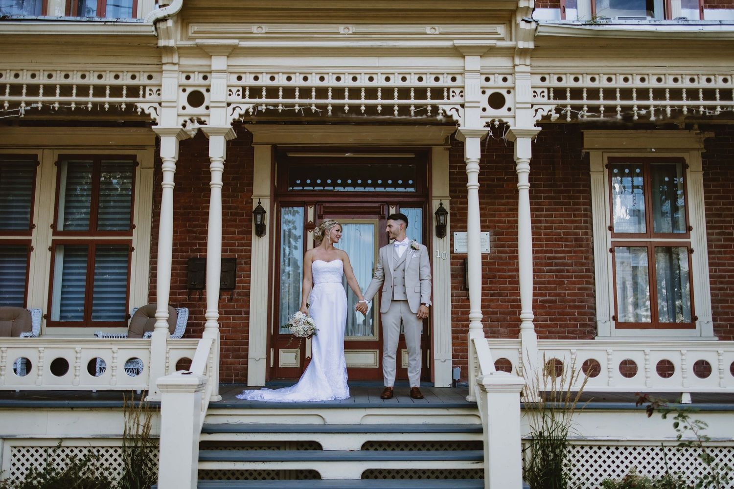Historic Victorian mansion with ornate white trim serves as elegant wedding venue backdrop.