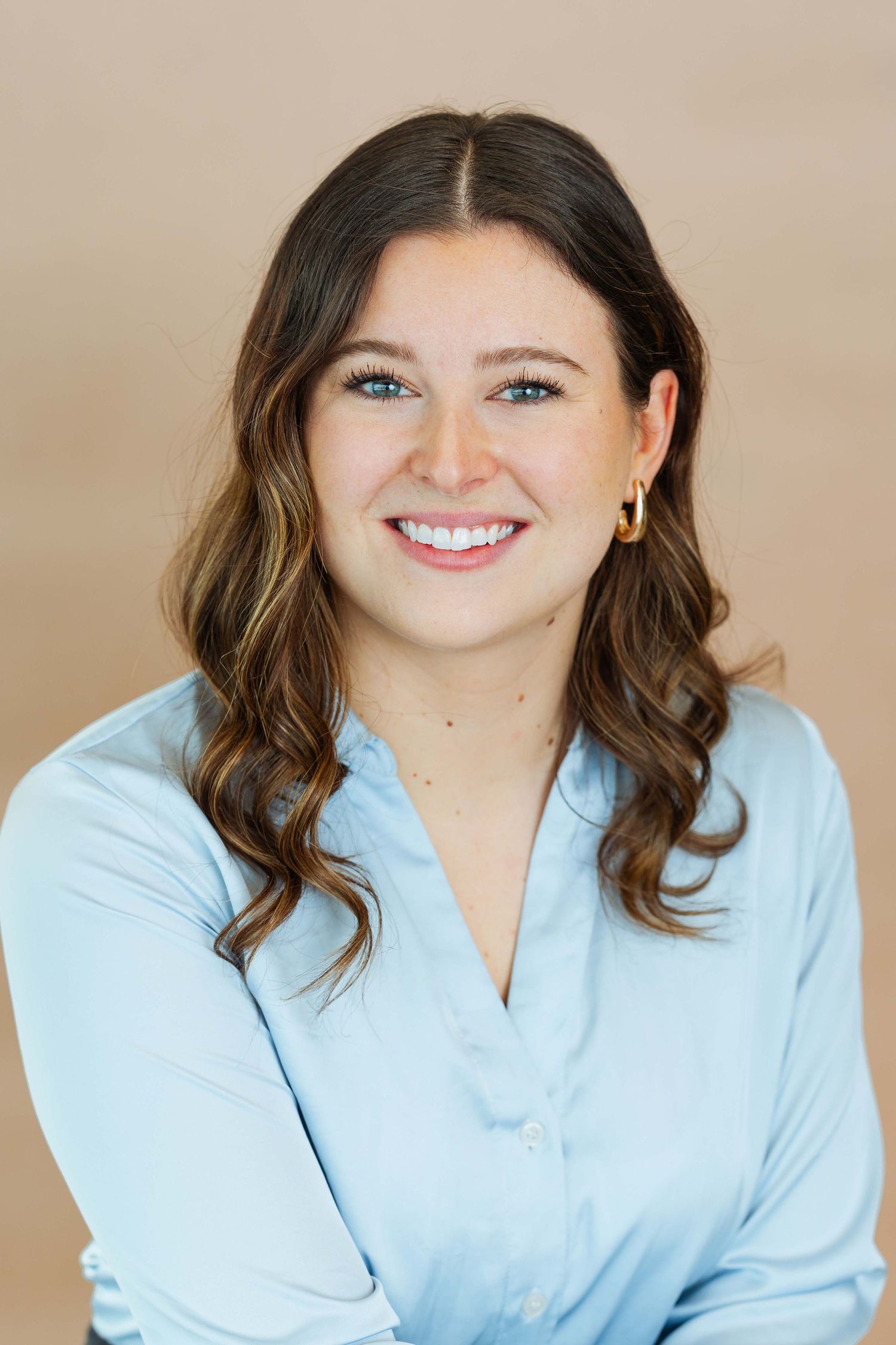 Professional headshot series showing person in light blue button-down shirt against neutral beige background.