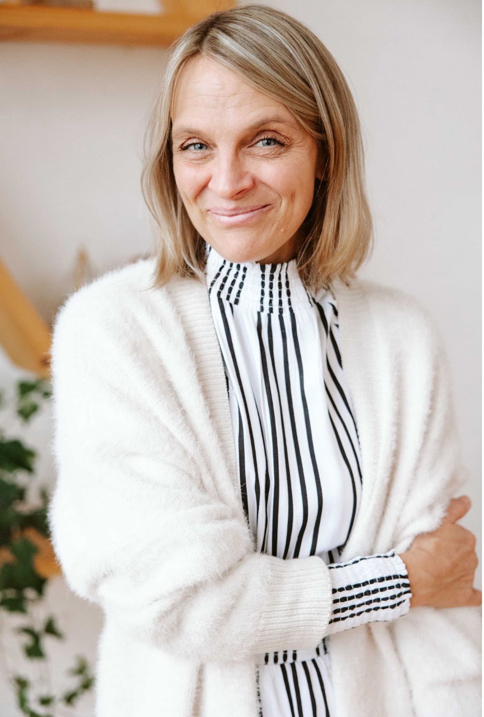 A series of photos showing someone wearing a cozy white sweater and black and white striped scarf in a bright room.