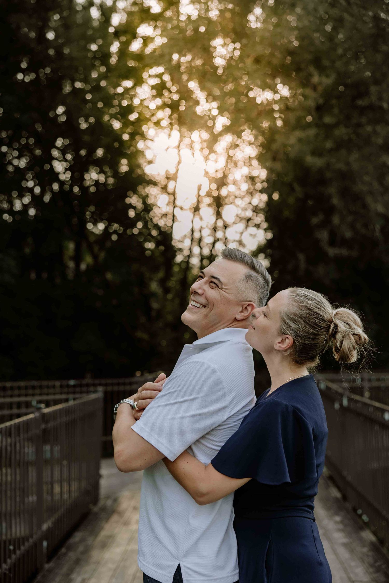 A couple shares joyful laughter while embracing during golden hour.