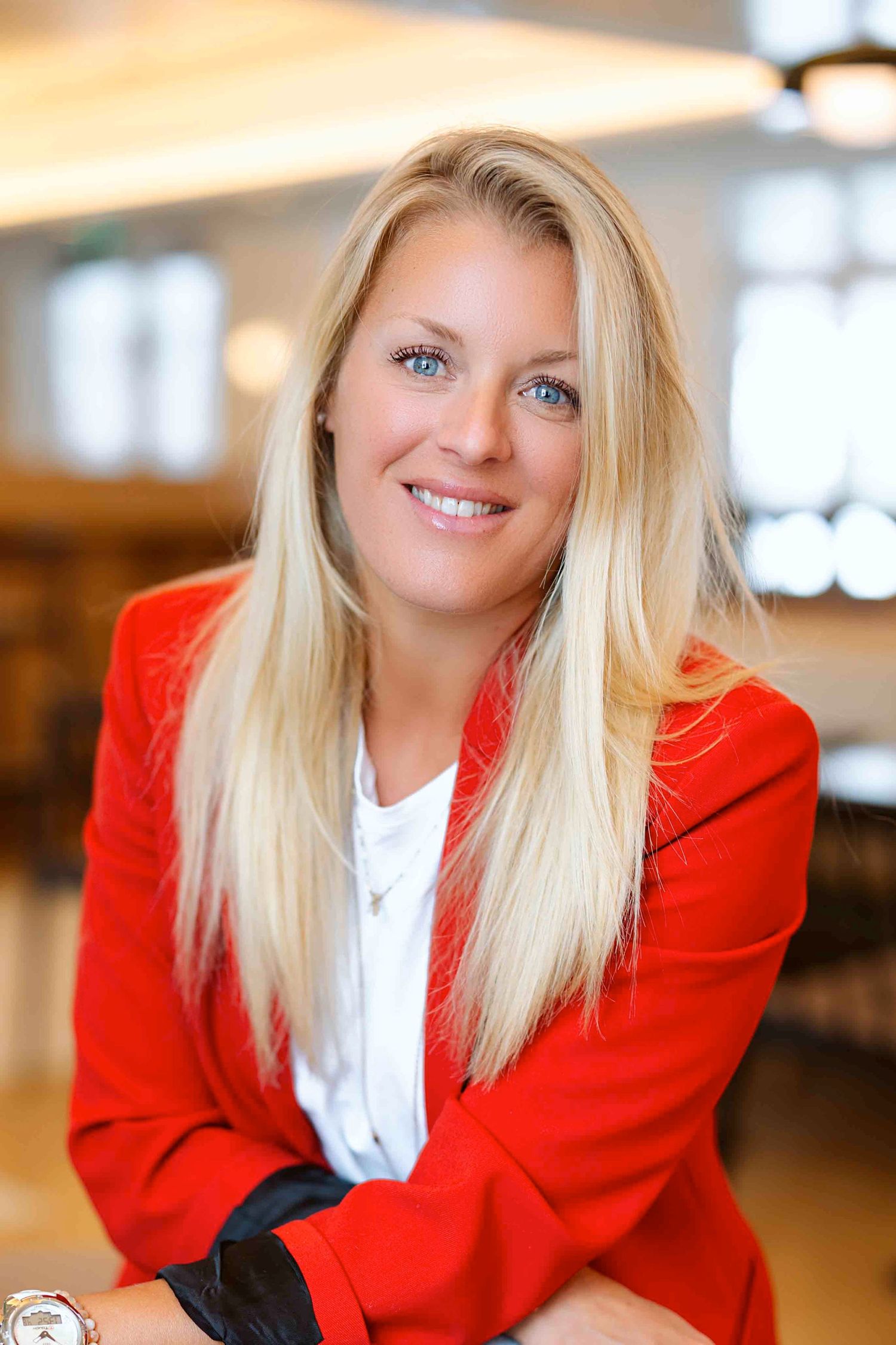 Professional portraits in bright red blazer and white blouse with warm lighting.