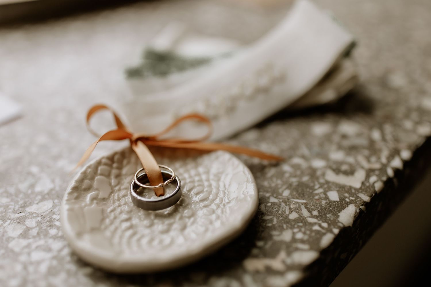 Wedding rings and delicate details photographed on textured lace surface in sepia tones.