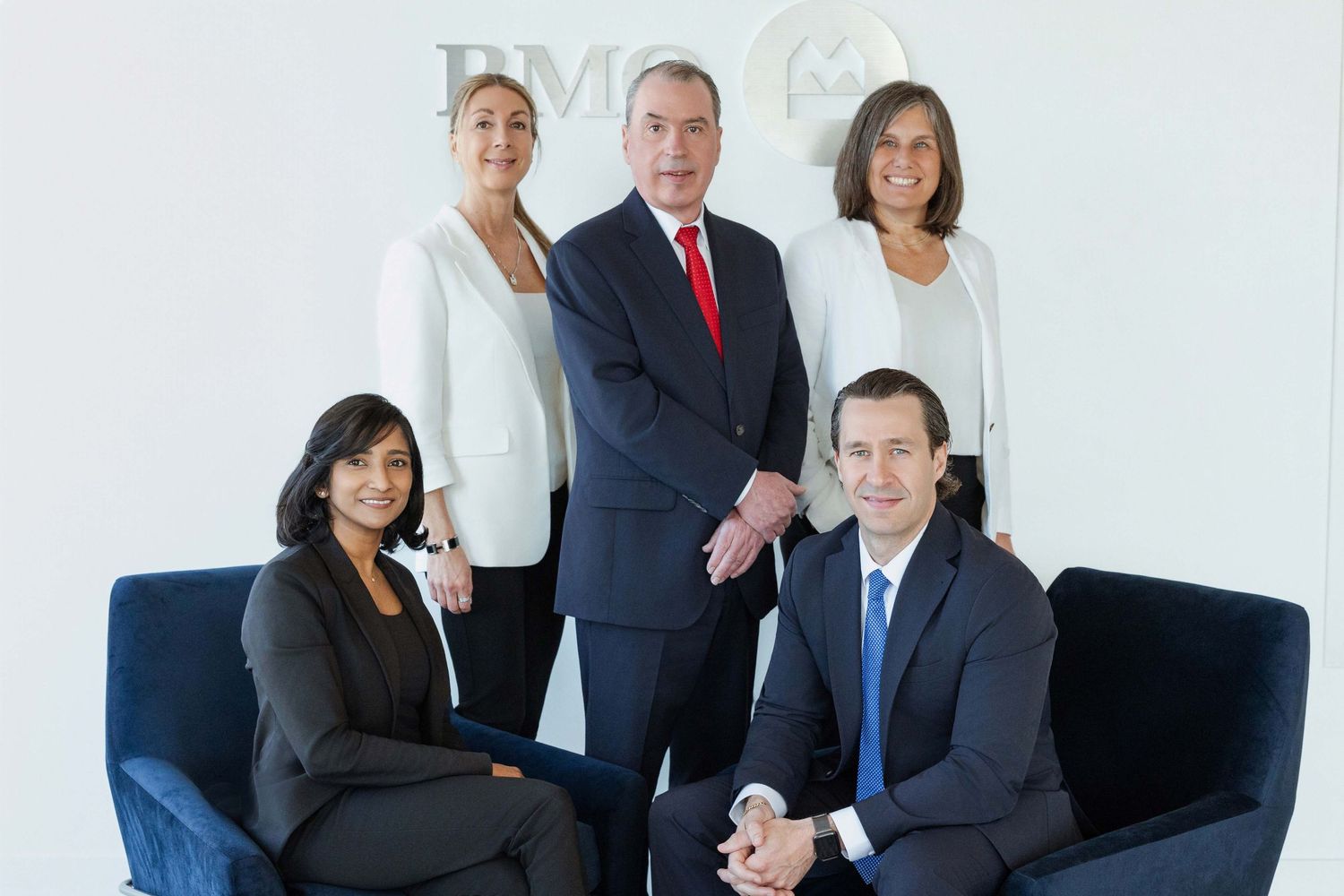 Five business professionals pose formally in an office setting with a BMO logo visible in the background.