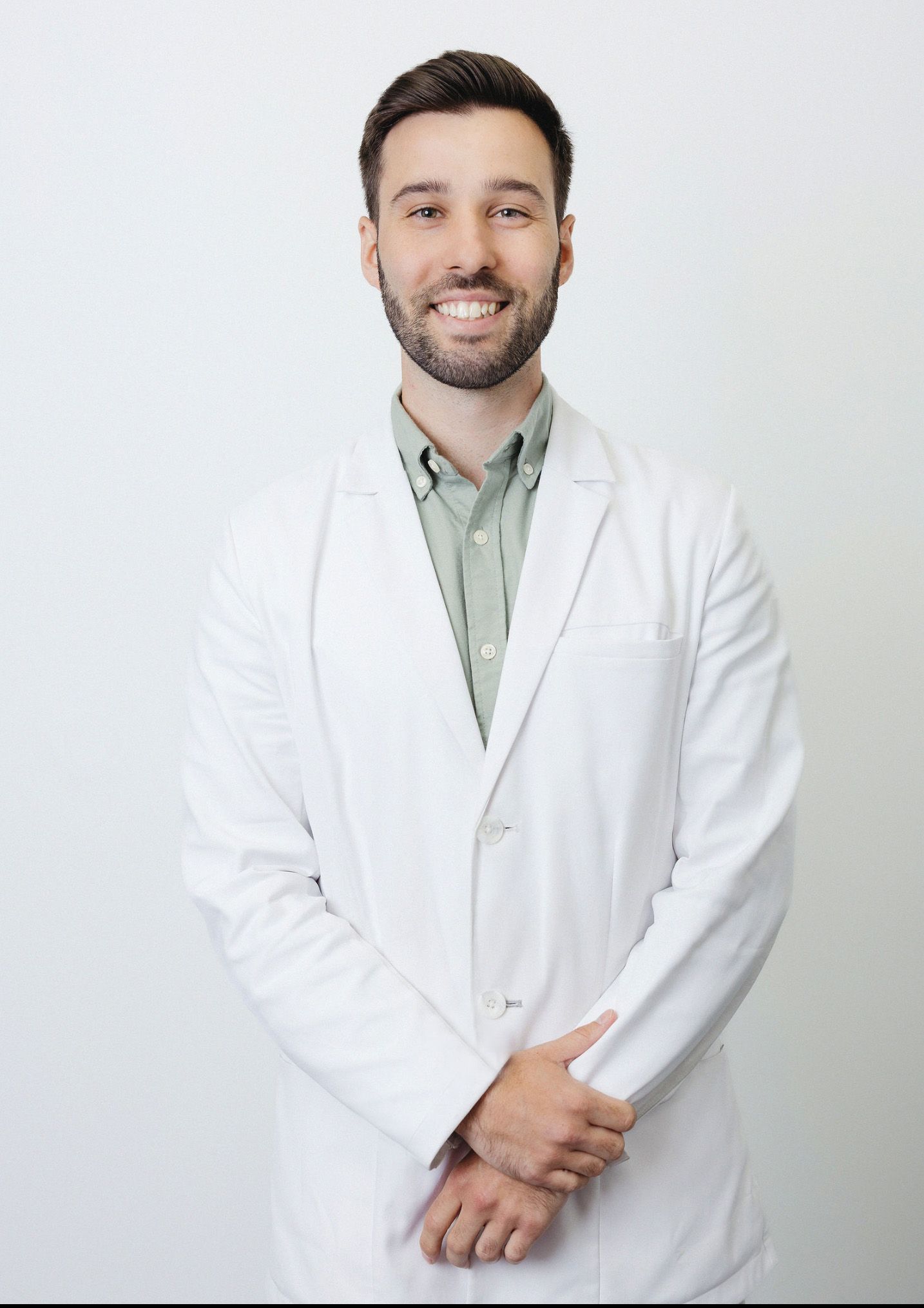 Medical professional in white coat posing against white background.