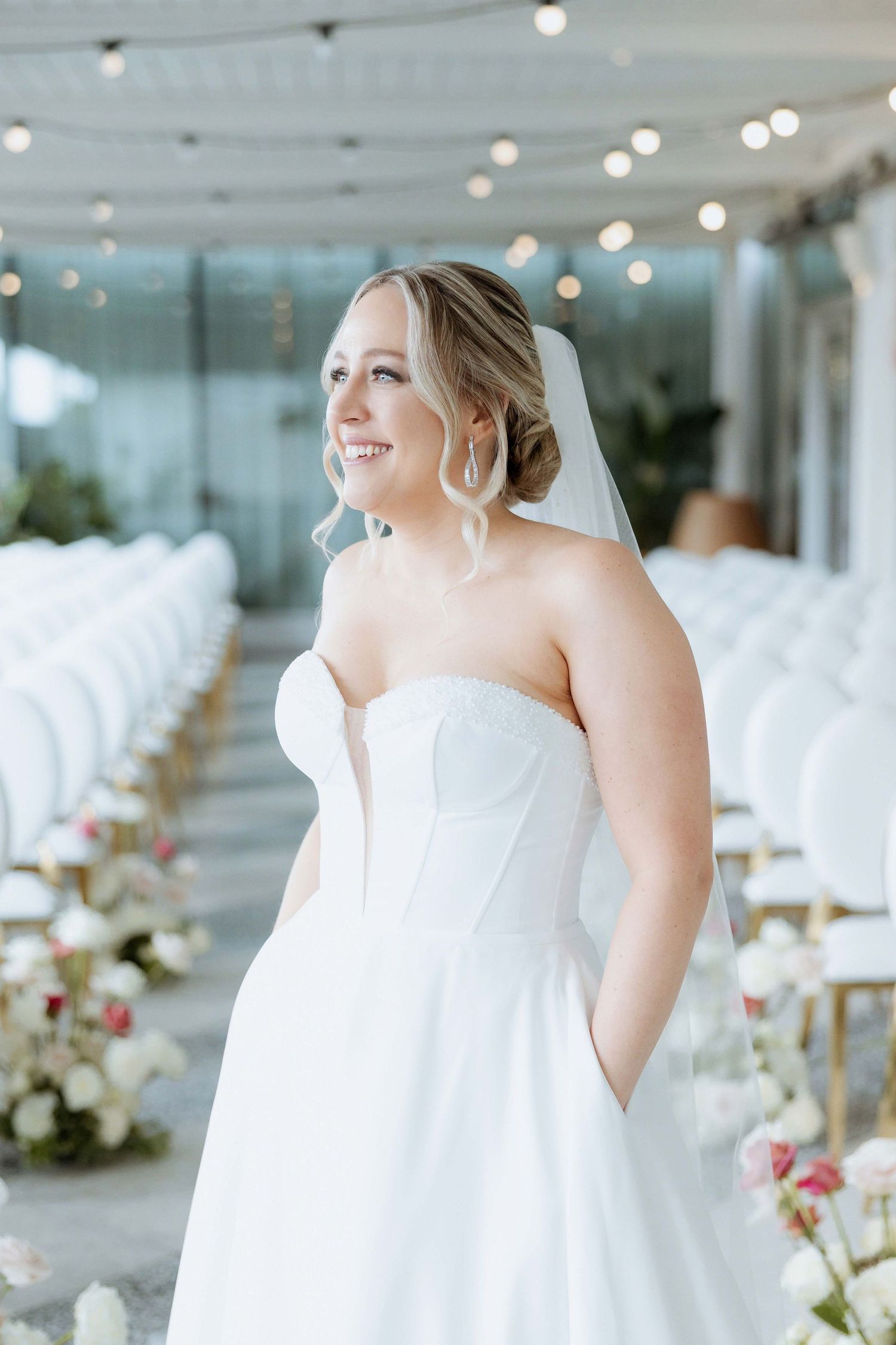 Elegant white wedding reception setup with string lights and floral arrangements creating a romantic atmosphere.