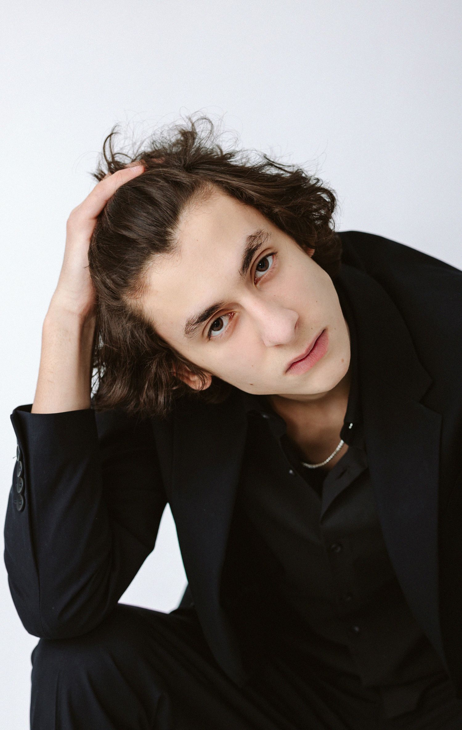 Portrait series of someone in a black sweater against a white background striking different poses.