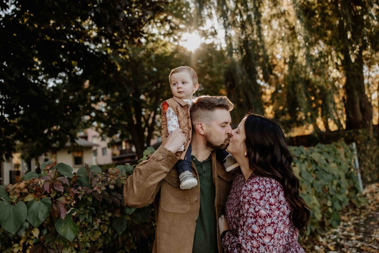 A family sharing a warm moment together during golden hour in a wooded setting.
