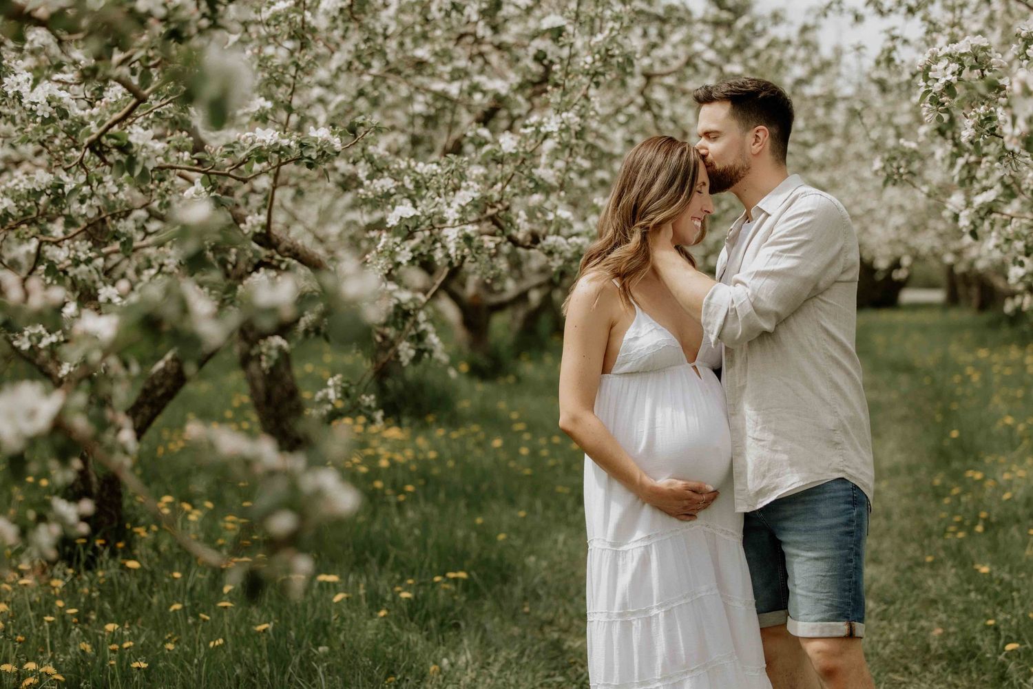 Romantic couple photoshoot in a blooming spring orchard with white flowers.