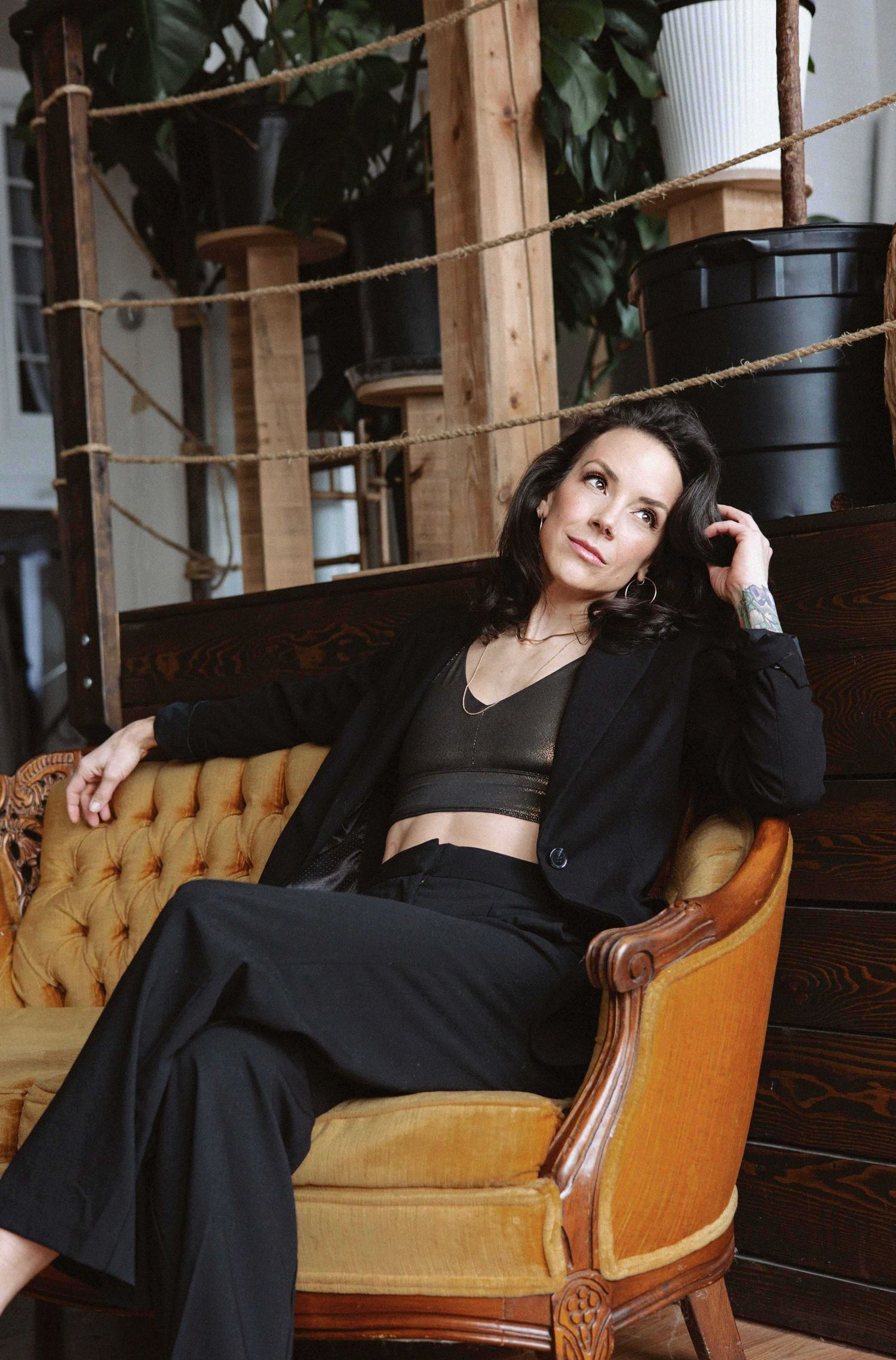 Dramatic portrait series of someone in black clothing posing on a vintage orange couch.