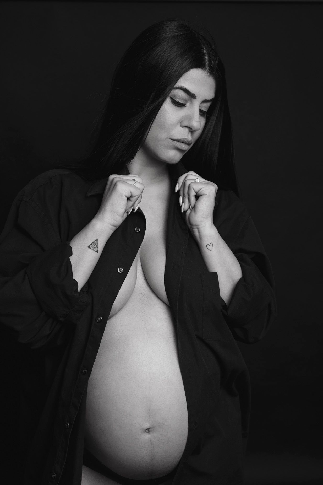 Artistic black and white maternity photos showing pregnant woman in dark flowing fabric.
