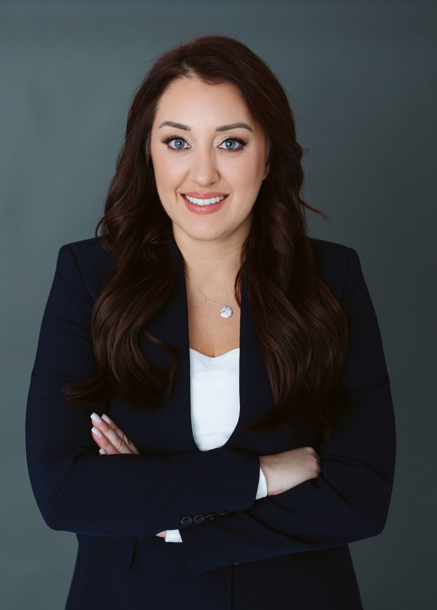 Professional headshot series showing person in navy blazer and white top against gray background with varied poses.