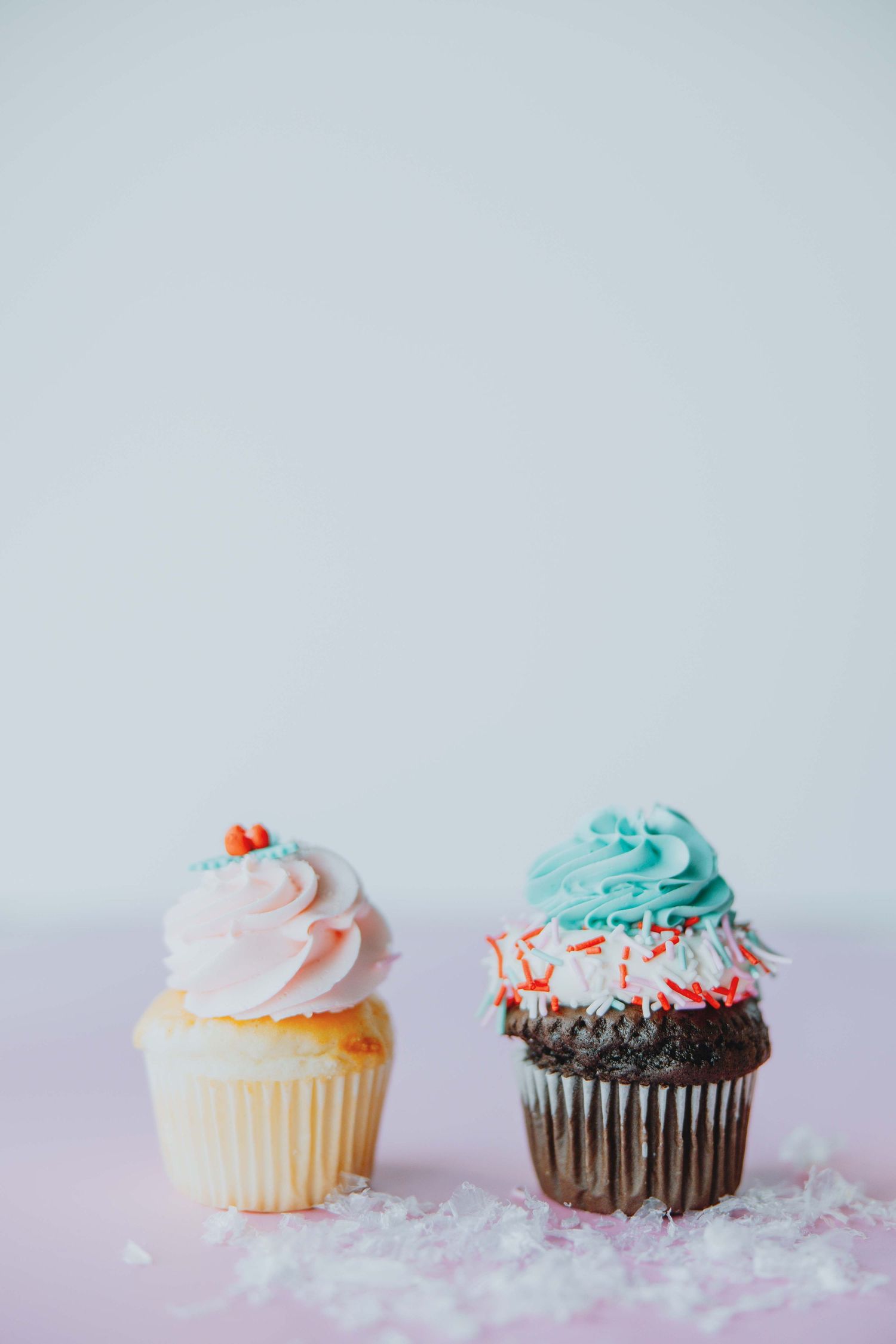 Colorful cupcakes with pink and turquoise frosting arranged on a light surface.