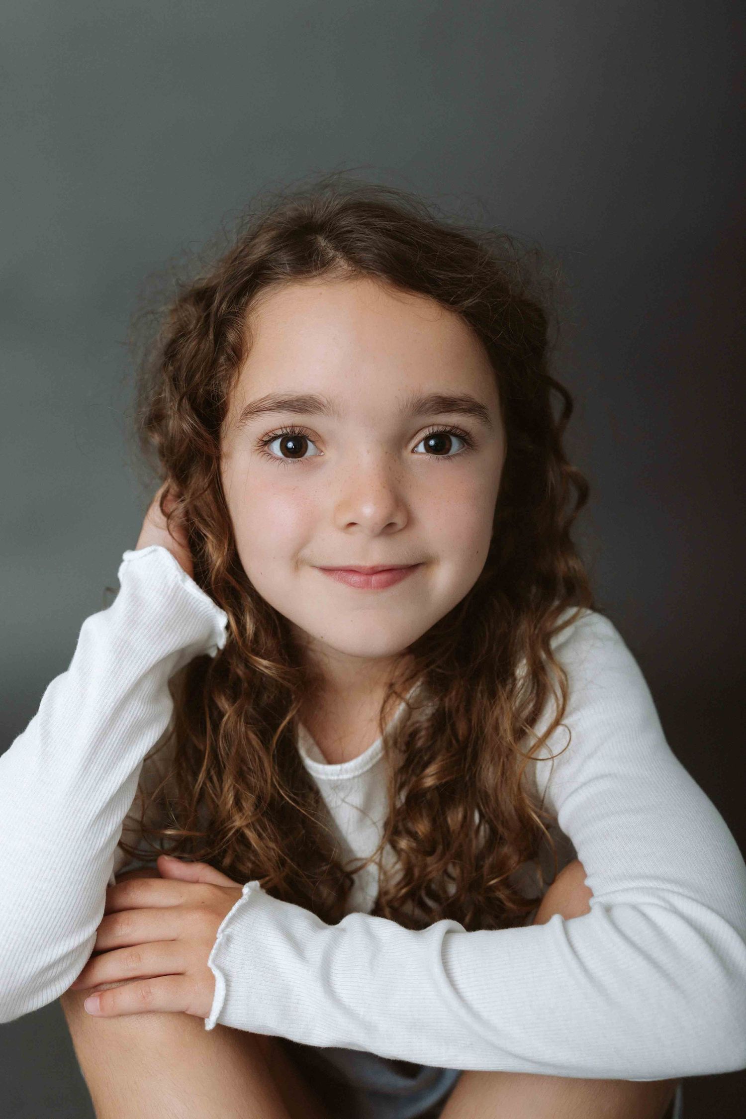 Portrait series showing playful expressions in white long sleeve top against gray background.