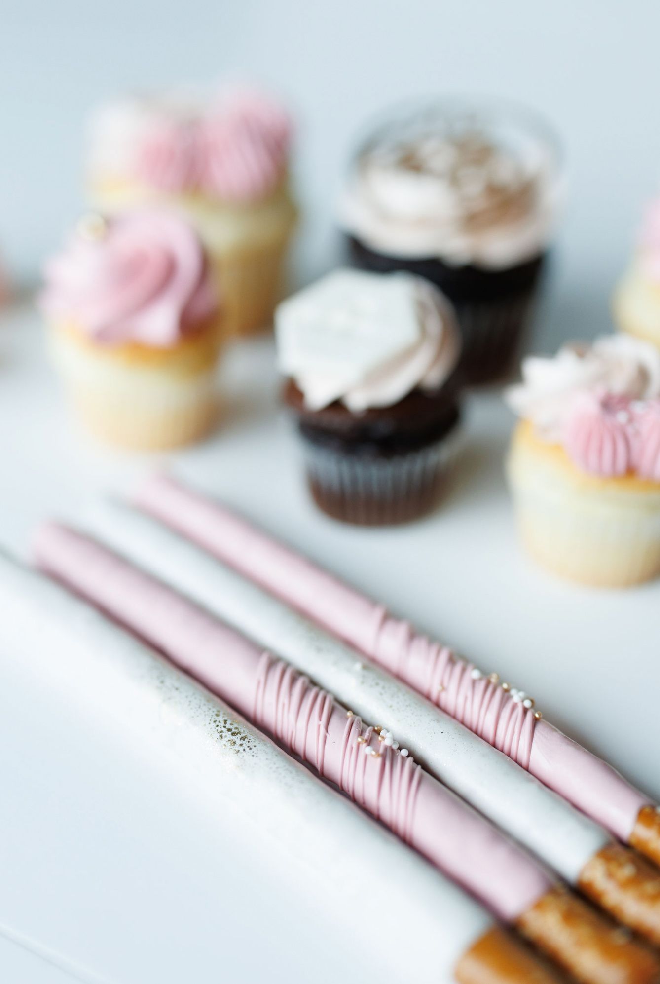 Pink frosted cupcakes and desserts with matching pink striped utensils.