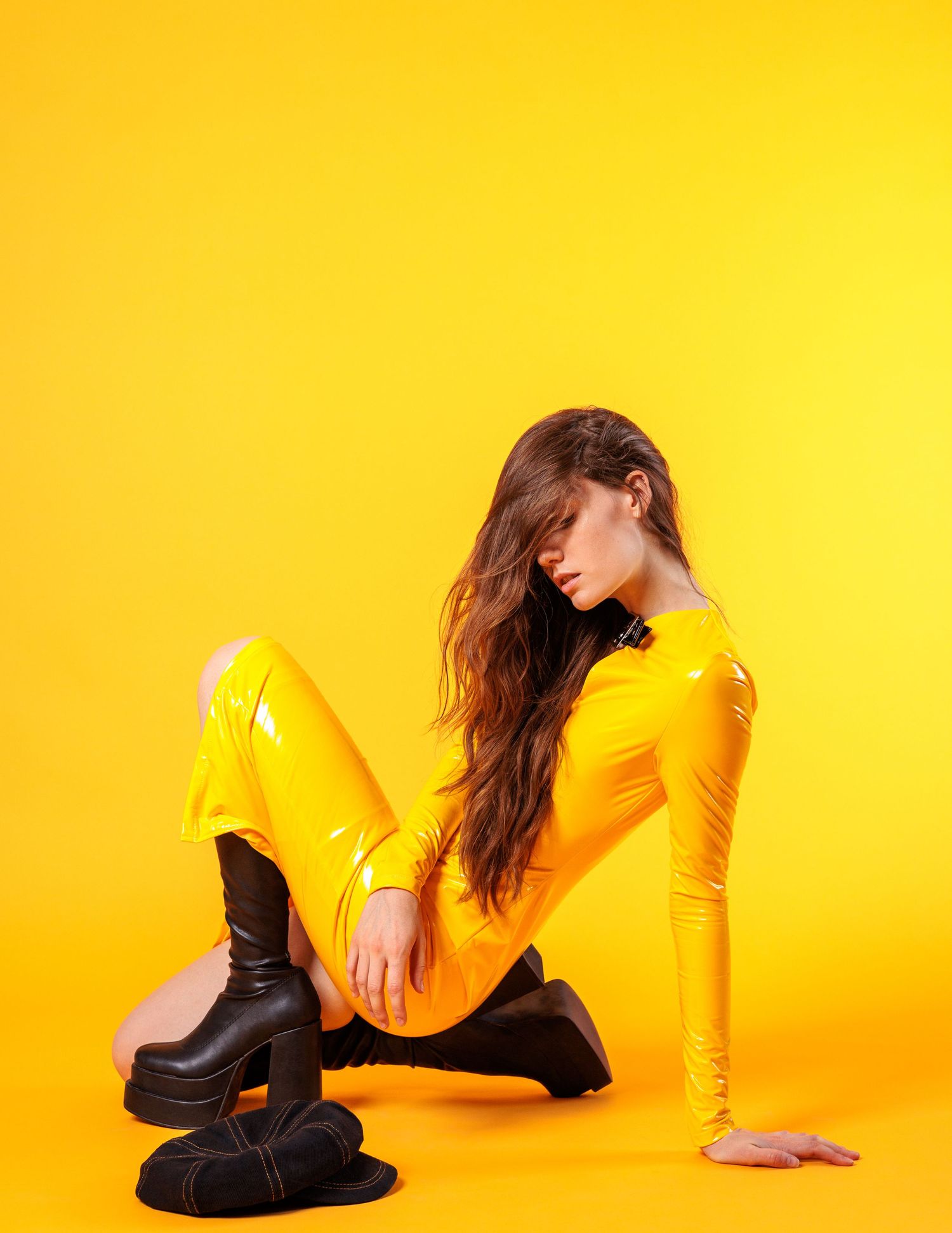 Yellow vinyl outfit with black boots photographed on vibrant yellow backdrop.