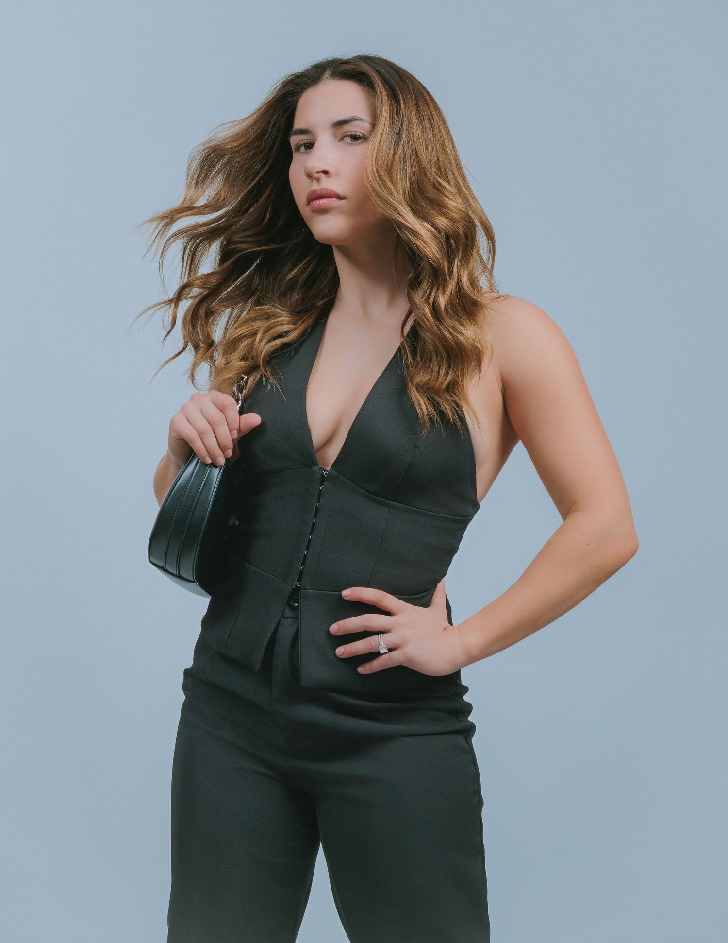 Model in black sleeveless jumpsuit poses against light gray background showing different angles and movement.