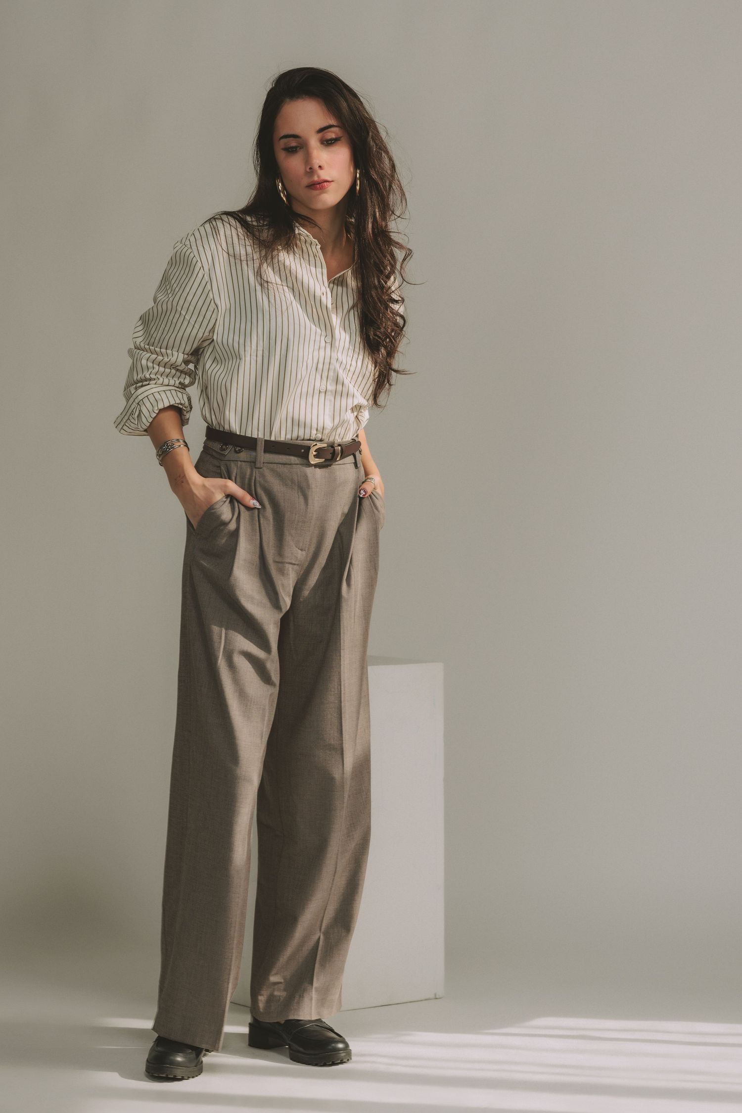 Professional fashion photo showing a striped button-down shirt paired with wide-leg khaki trousers and a brown belt.