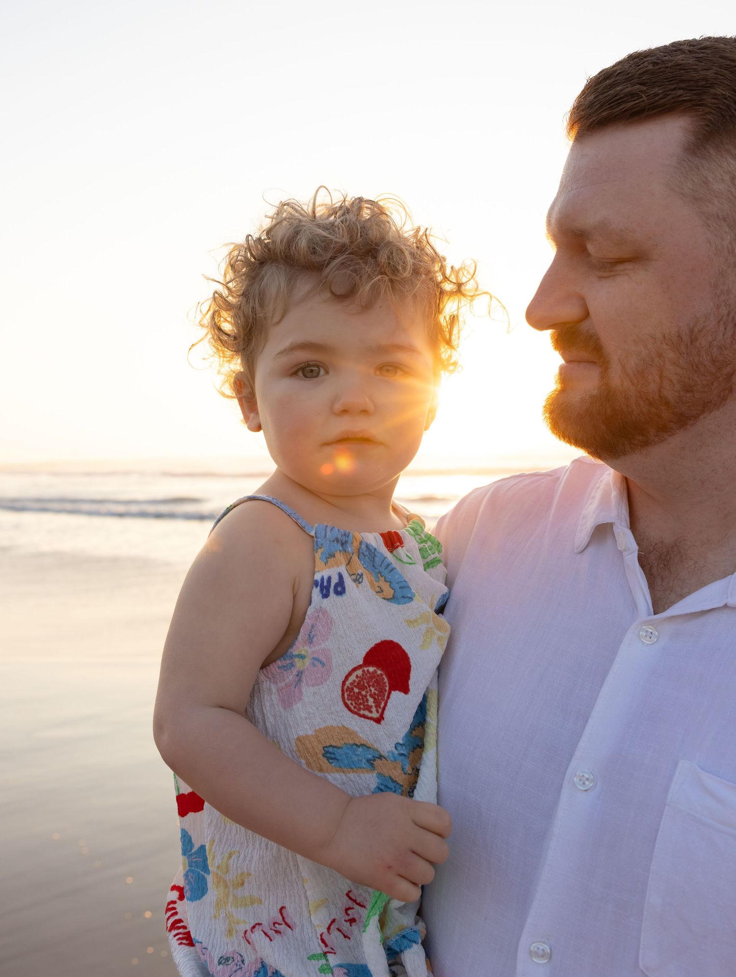 Father and daughter enjoy a cuddle as the warmth of the rising sun shines through between them.