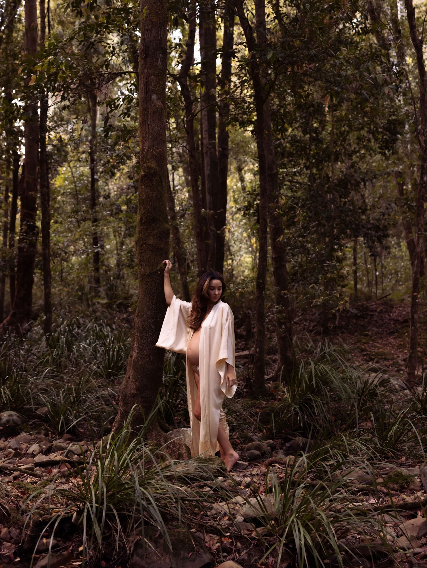 Maternity mother stands leaning against a tree in the forest at Glenrock, Newcastle.