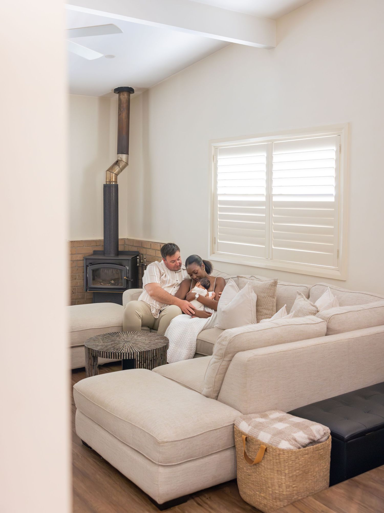 In home newborn photography session with mum, dad and baby snuggled on the lounge together in their house in Newcastle.
