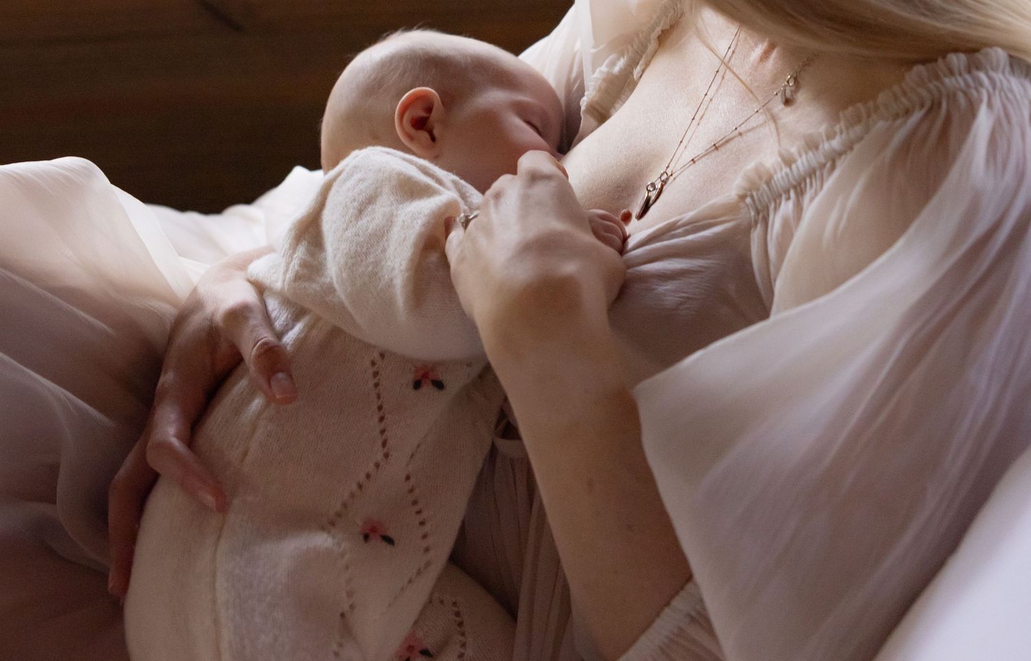 Mother breastfeeding her baby in the soft morning light in their house.