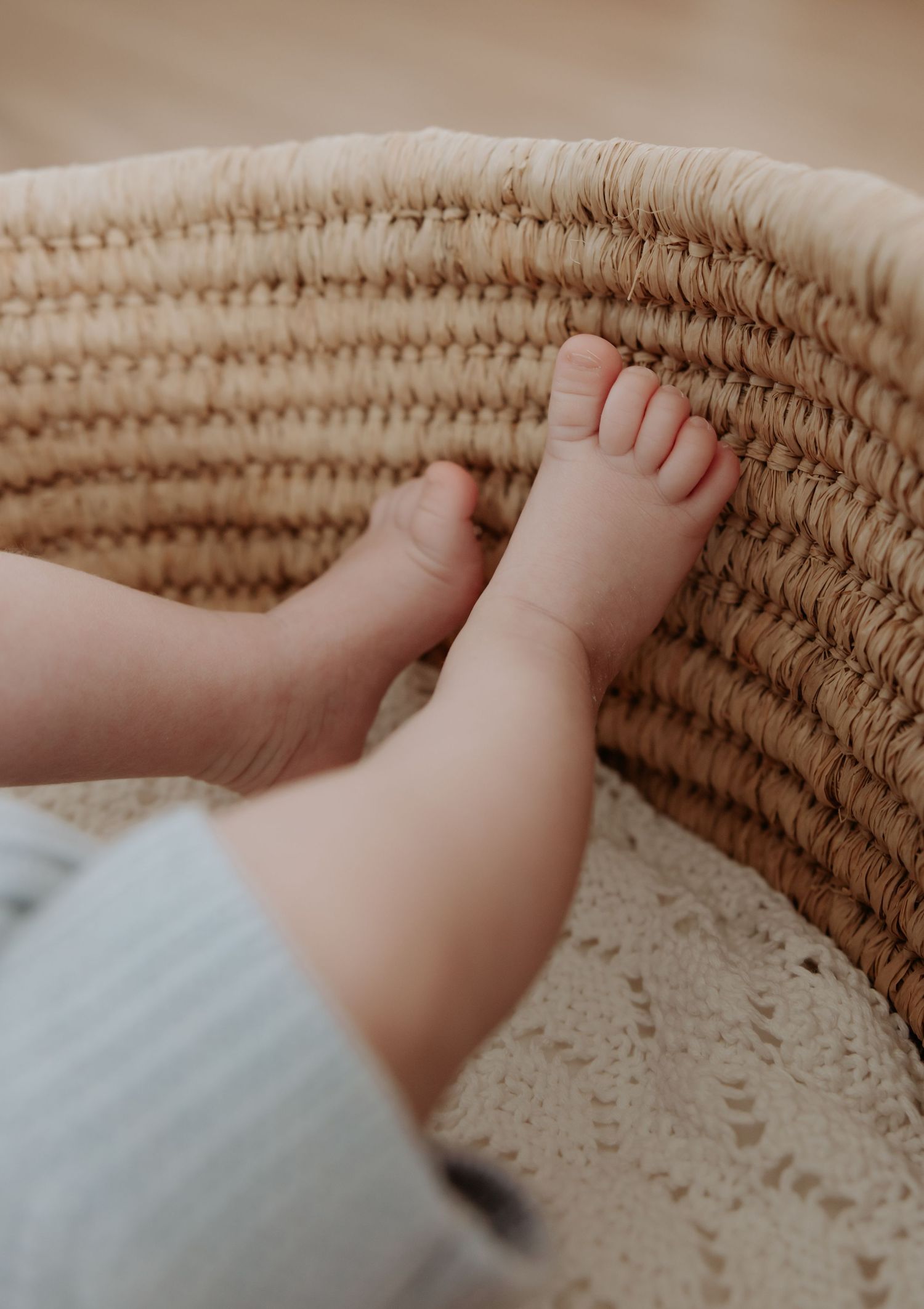 Newborn baby toes resting inside a woven baby basket.