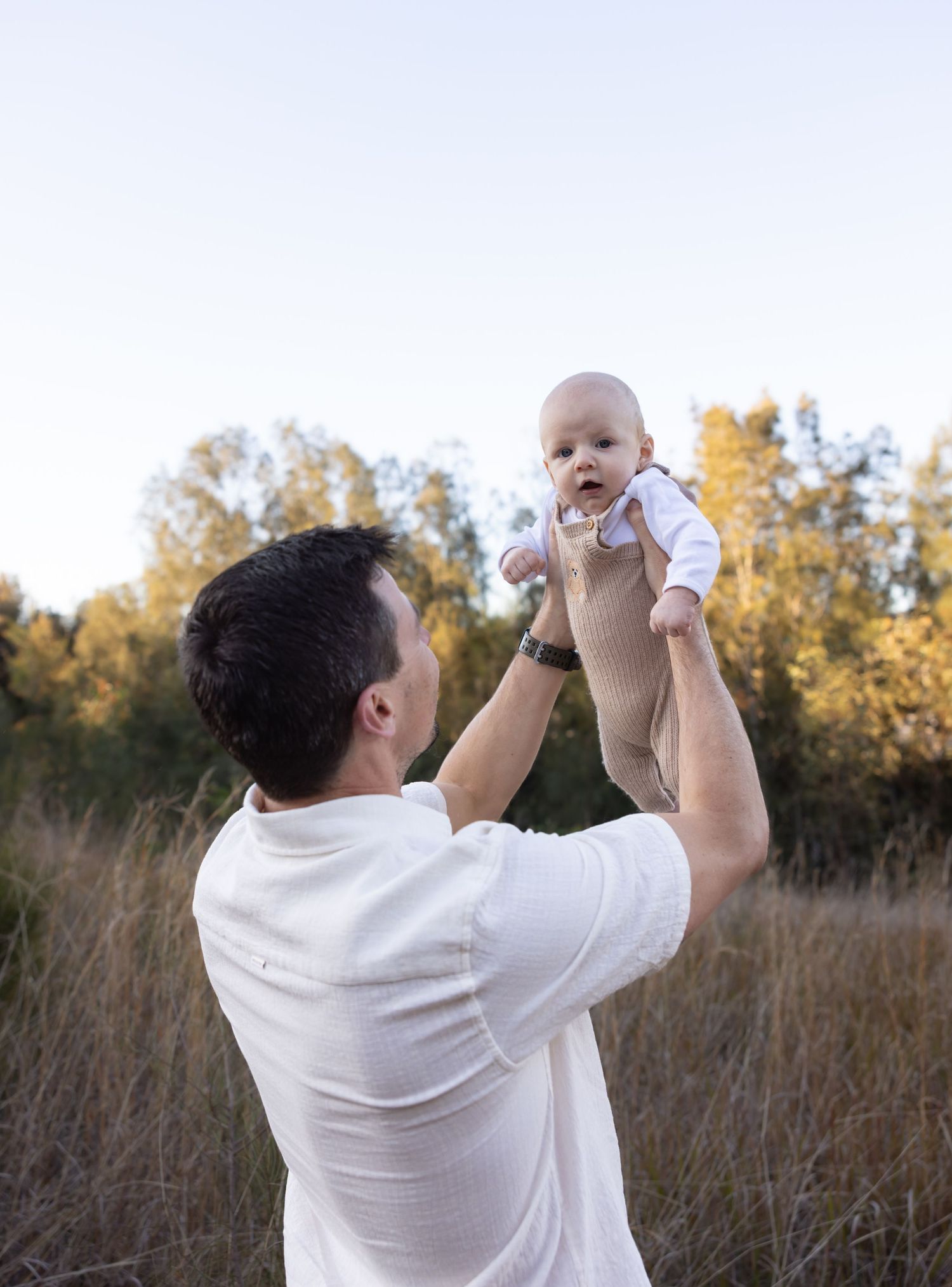 Father holding his baby up high while baby smiles, taken in Lake Macquarie.