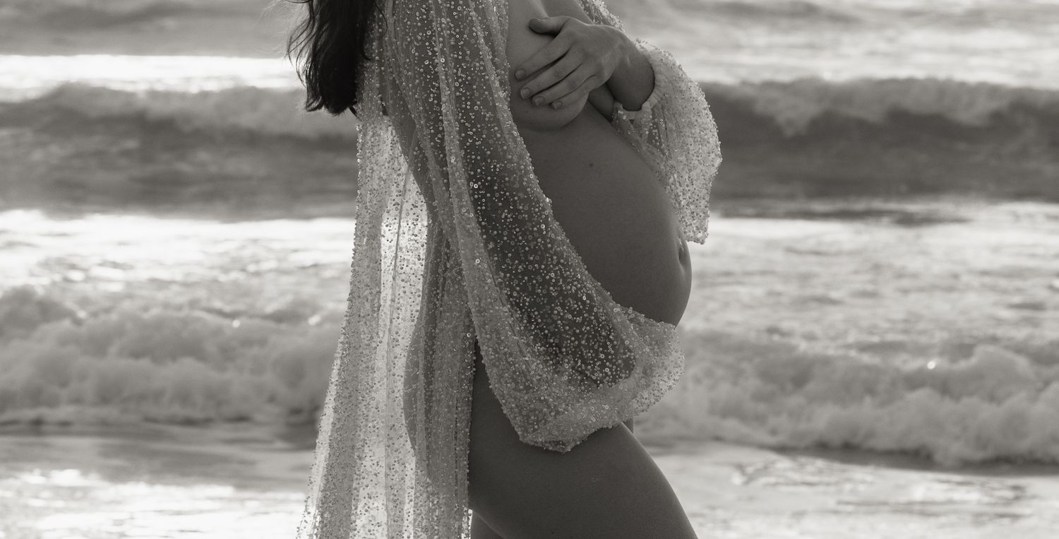 Close up of mother's pregnant belly surrounded by sequin and sparkle fabric.