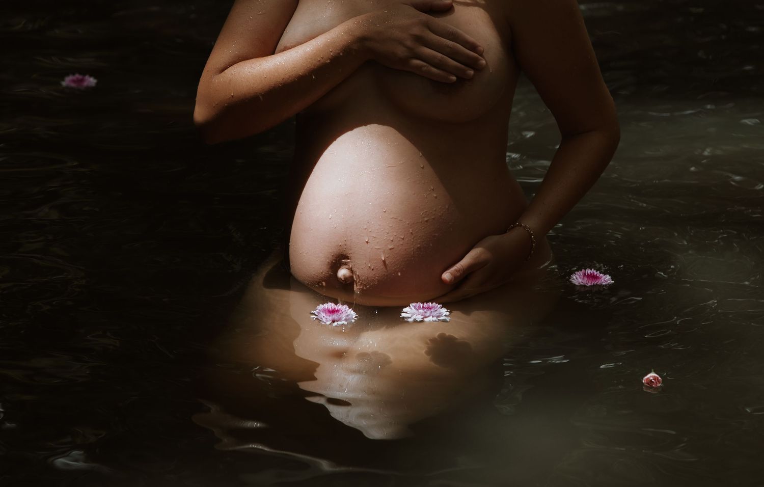Flowers float around pregnant mother's belly artistically showing that her growing baby is a girl.