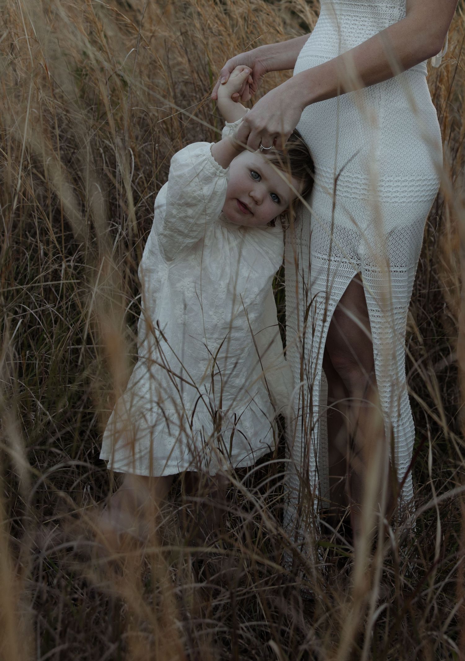 Child holds hands with mum n the tall grass in Lake Macquarie. Soft warm golden brown tones.